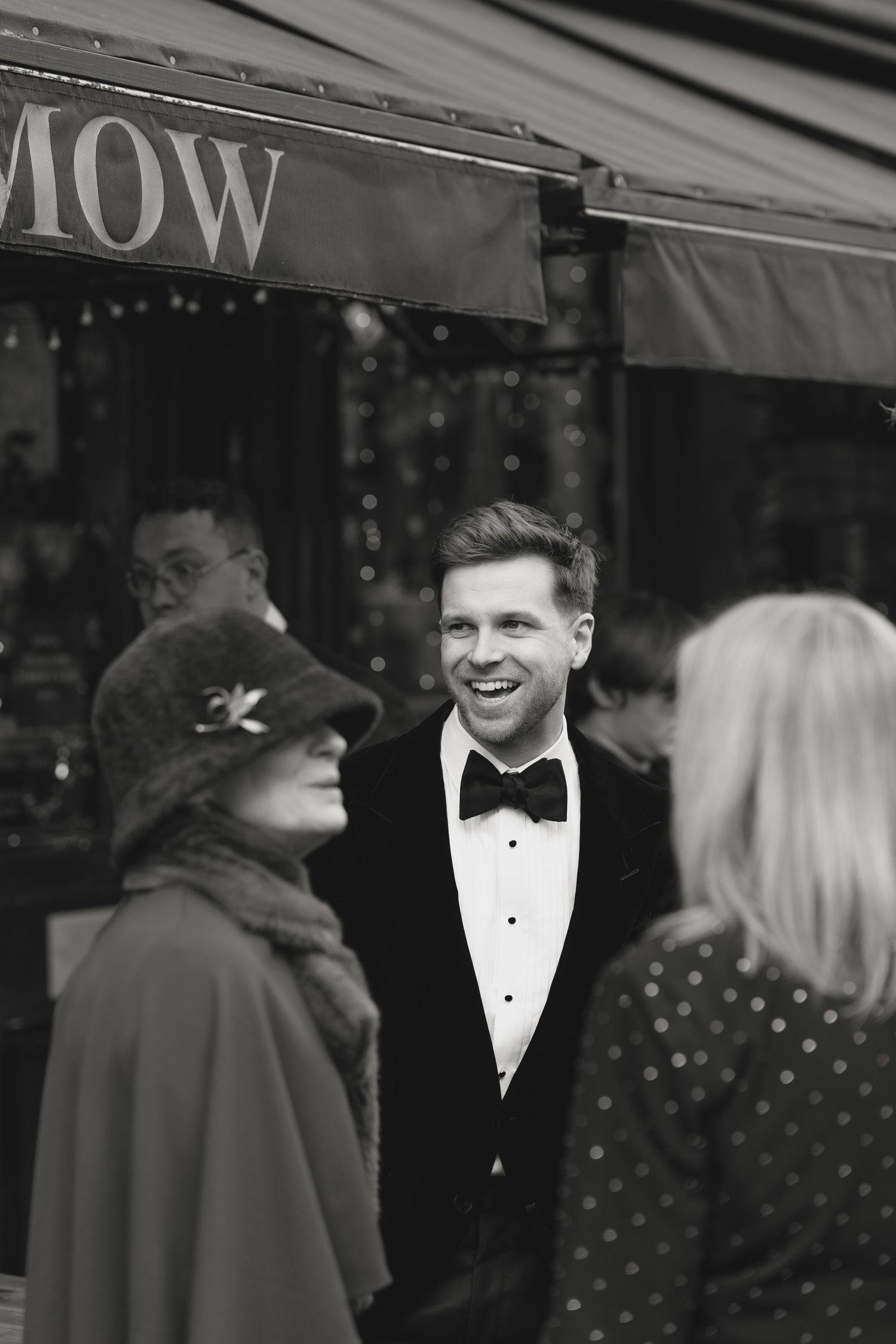 People in formal attire gathering outside The Barley Mow on a winter evening.