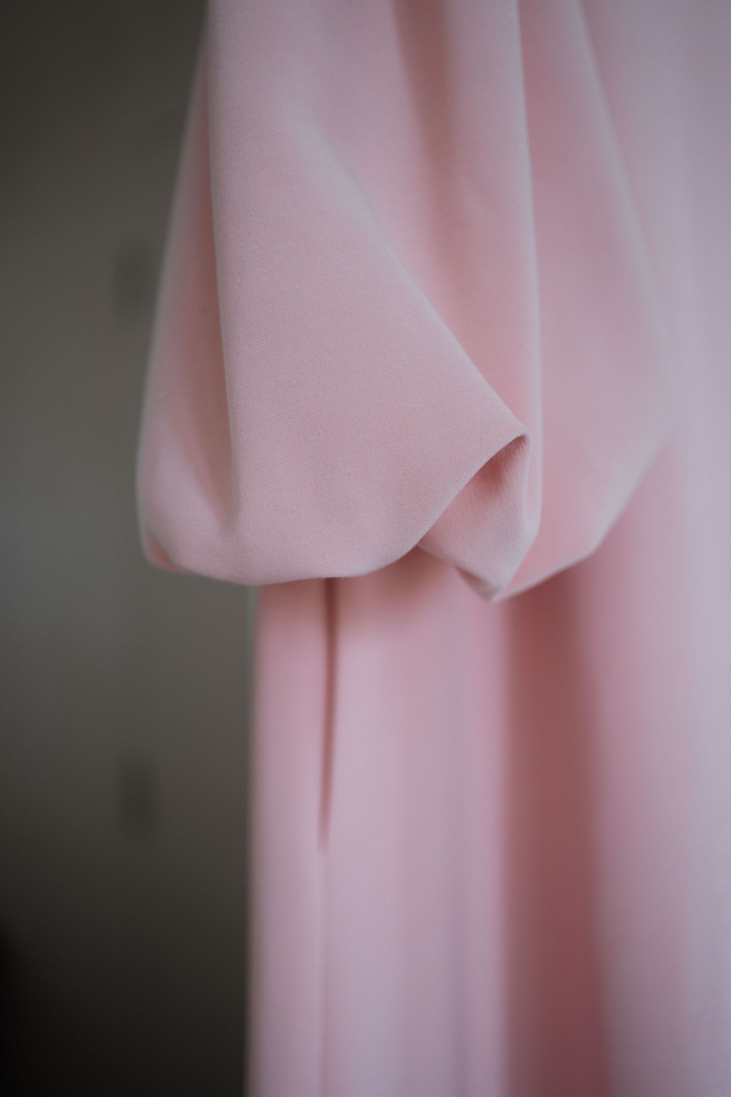 Close-up abstract view of flowing pink fabric with soft folds.