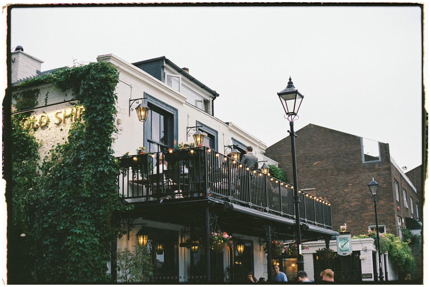 Historic brick buildings with lamp posts and balconies line a charming street at dusk.