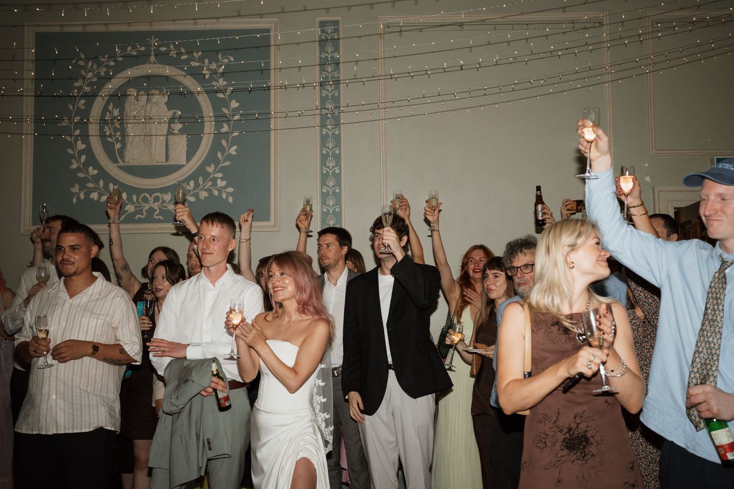 Wedding reception dance floor with guests dancing under decorative lighting.