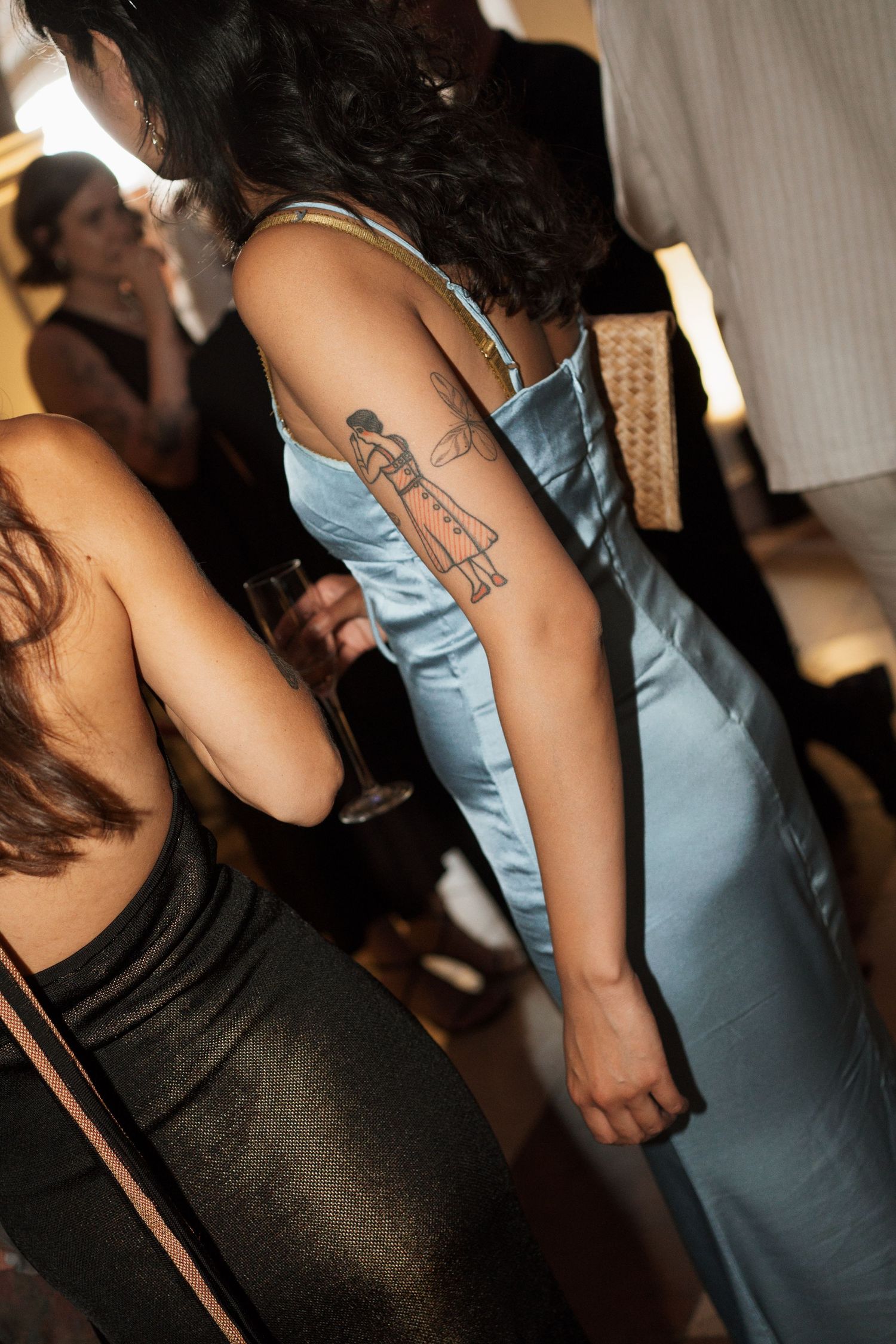 Close-up details of formal dresses in light blue and black at an evening event.