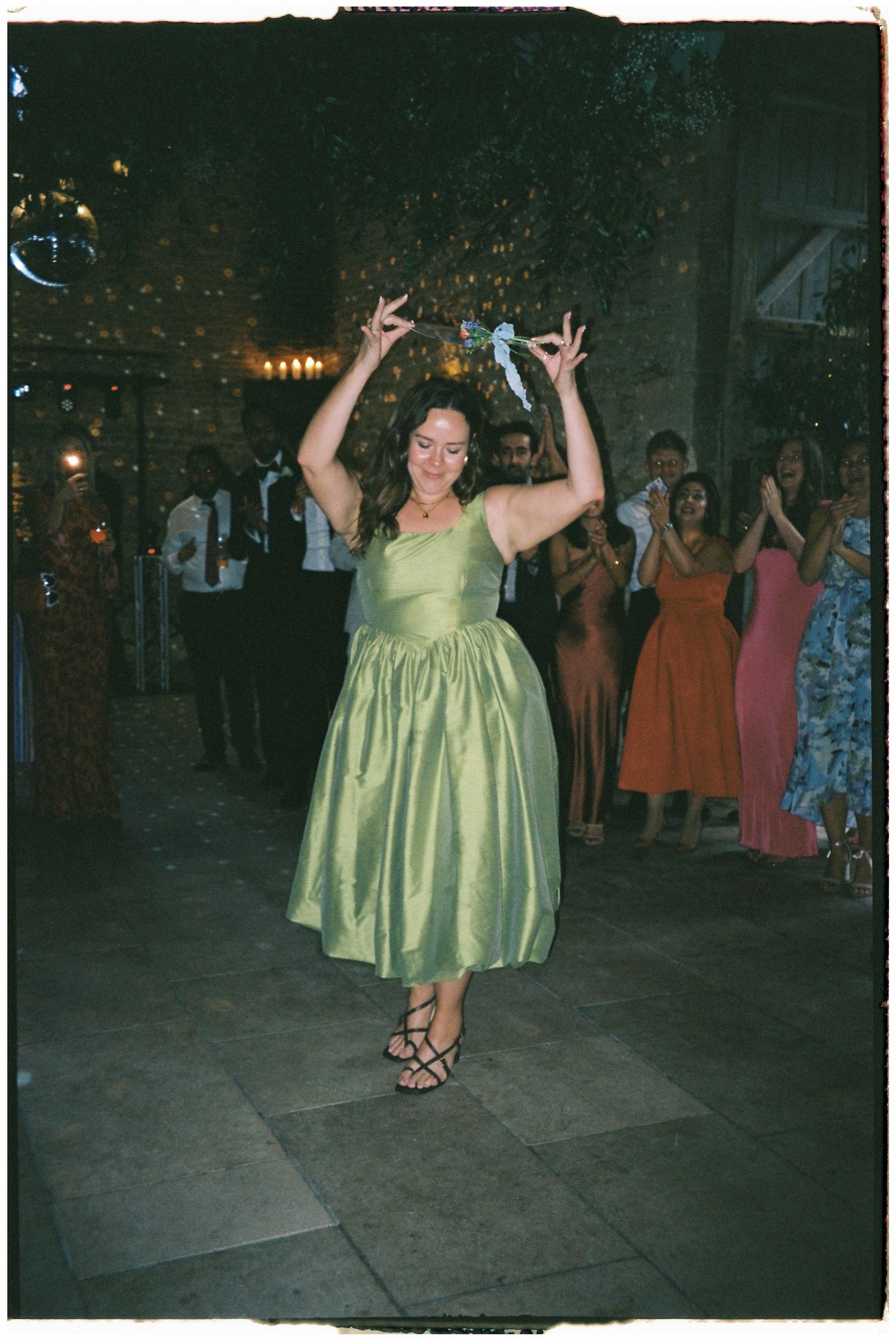 Person in a mint green dress dancing joyfully at a wedding reception.