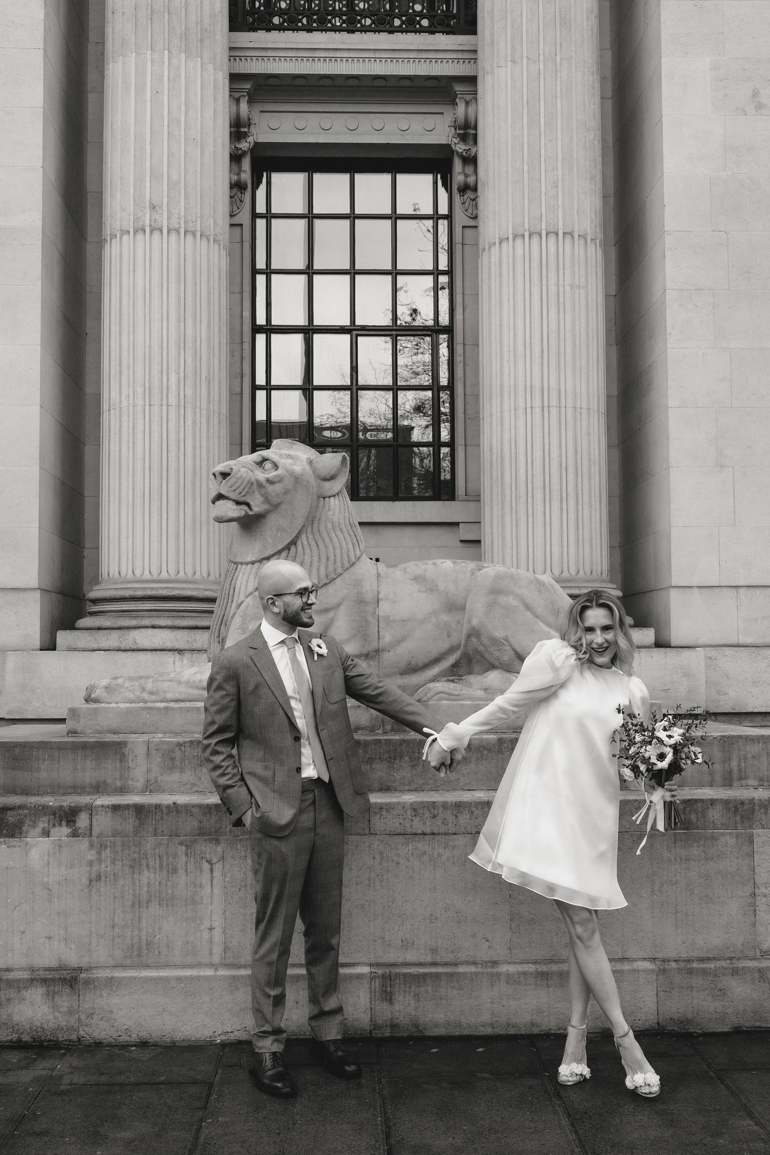Playful black and white wedding portraits against classical architecture.