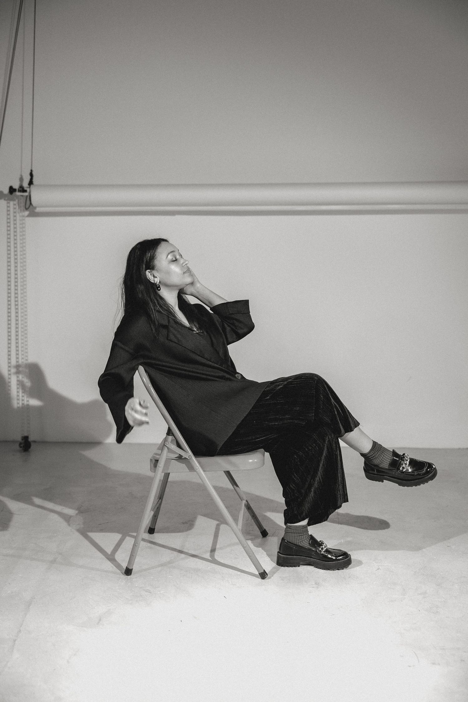 Artistic black and white photo sequence of person reclining in metal folding chair.