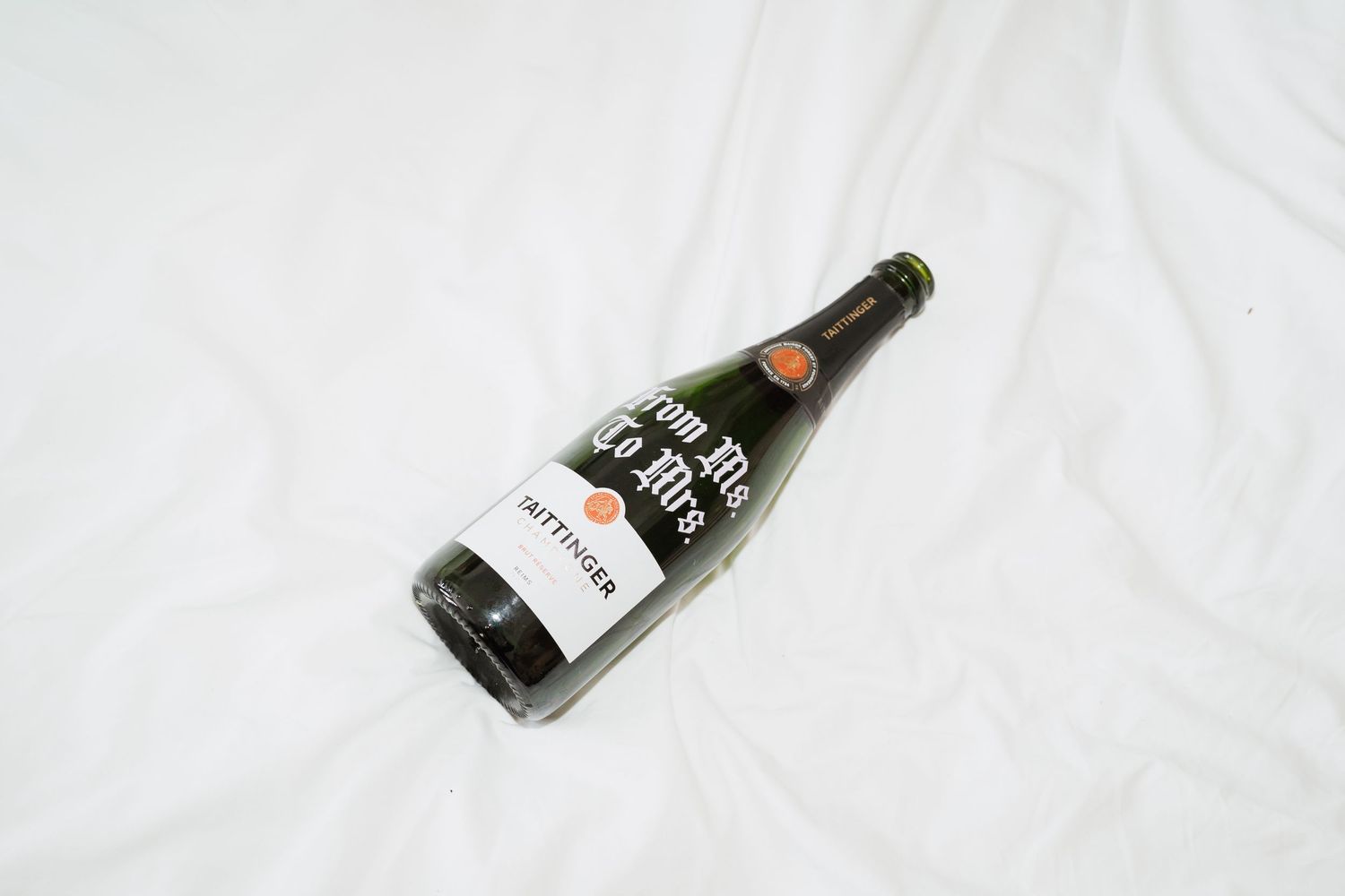 A single wine bottle with a black and white label lying on its side against a white background.