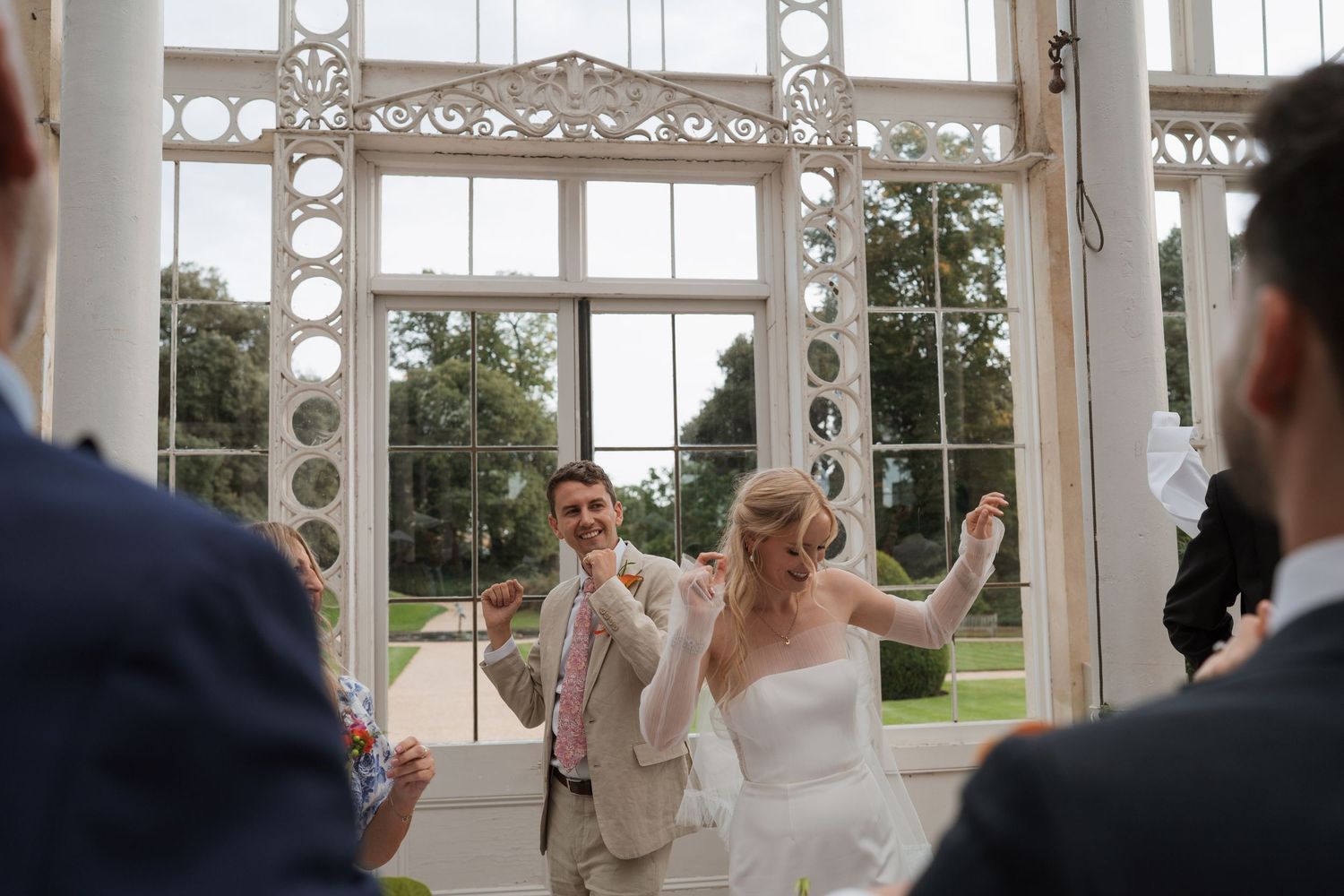 Celebratory moment in an ornate white conservatory with decorative ironwork details.