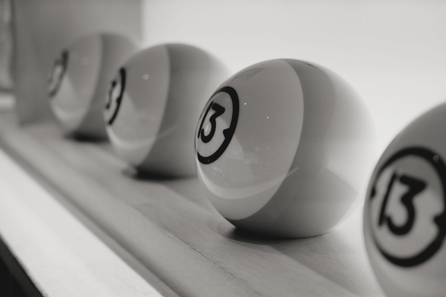 Row of white bowling balls with numbers displayed on a shelf.