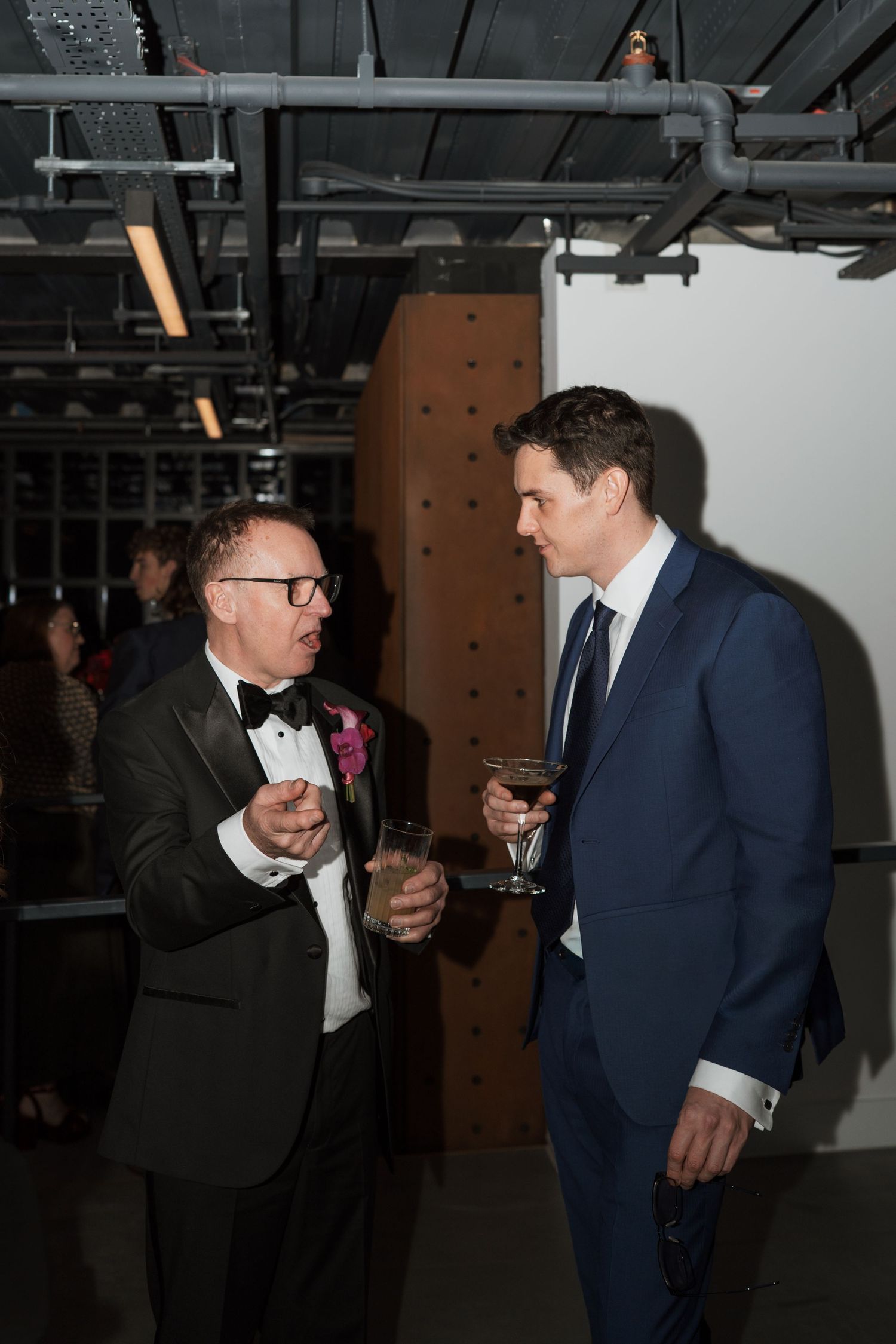 Evening reception gathering with guests in formal attire mingling and holding drinks.