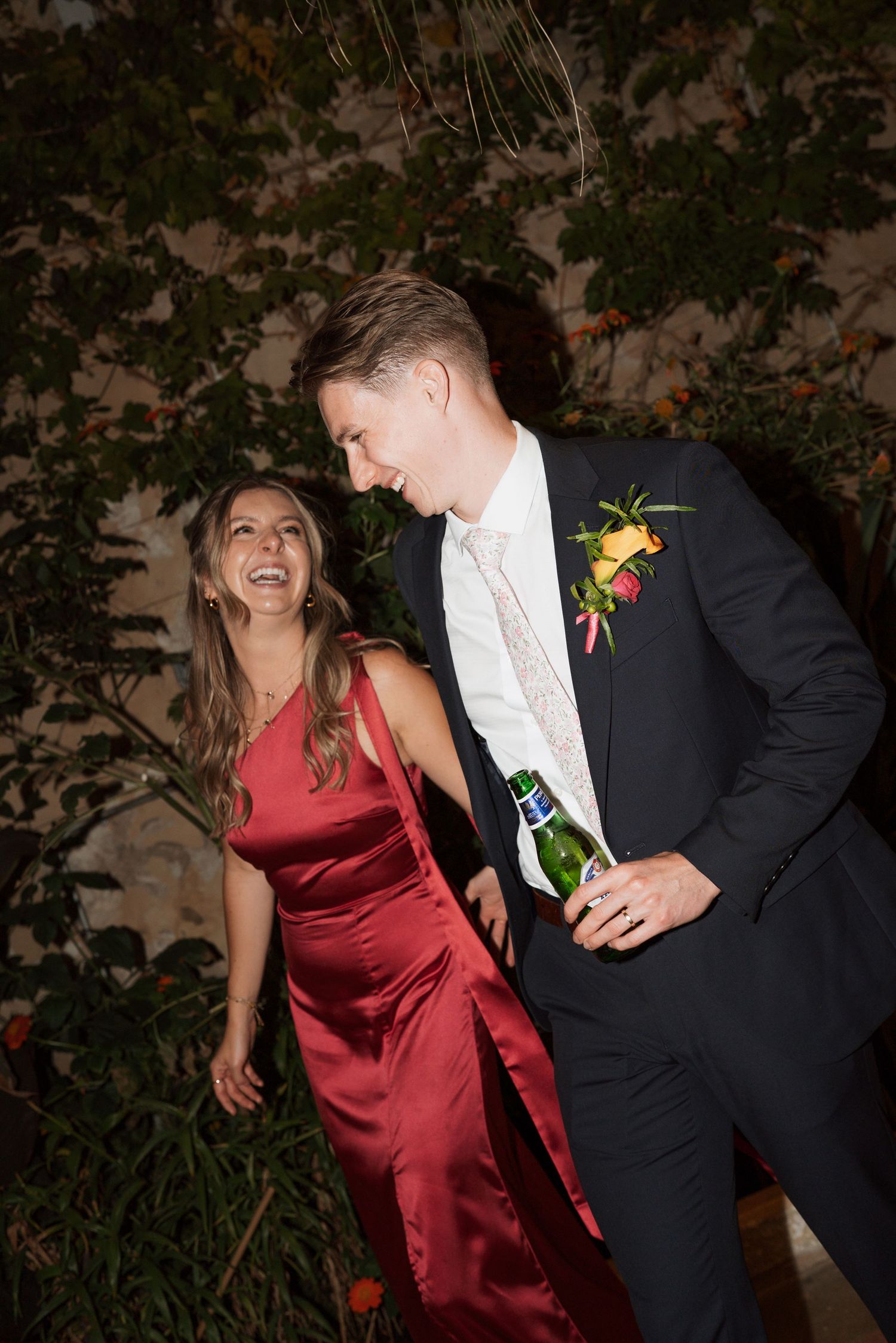 Couple dancing together at a wedding reception, with the woman wearing a red dress.