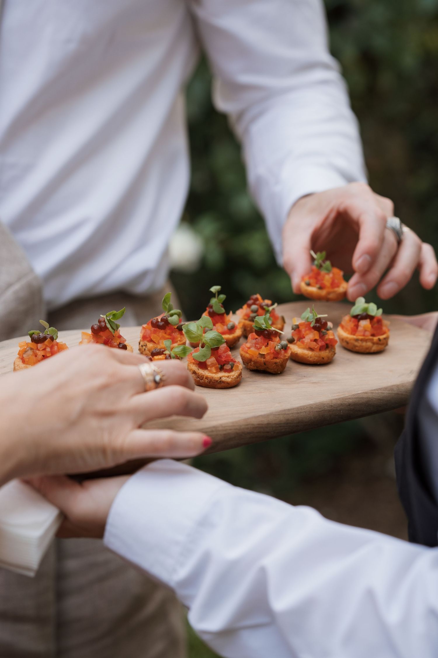 Catering staff presents appetizers on wooden serving boards.