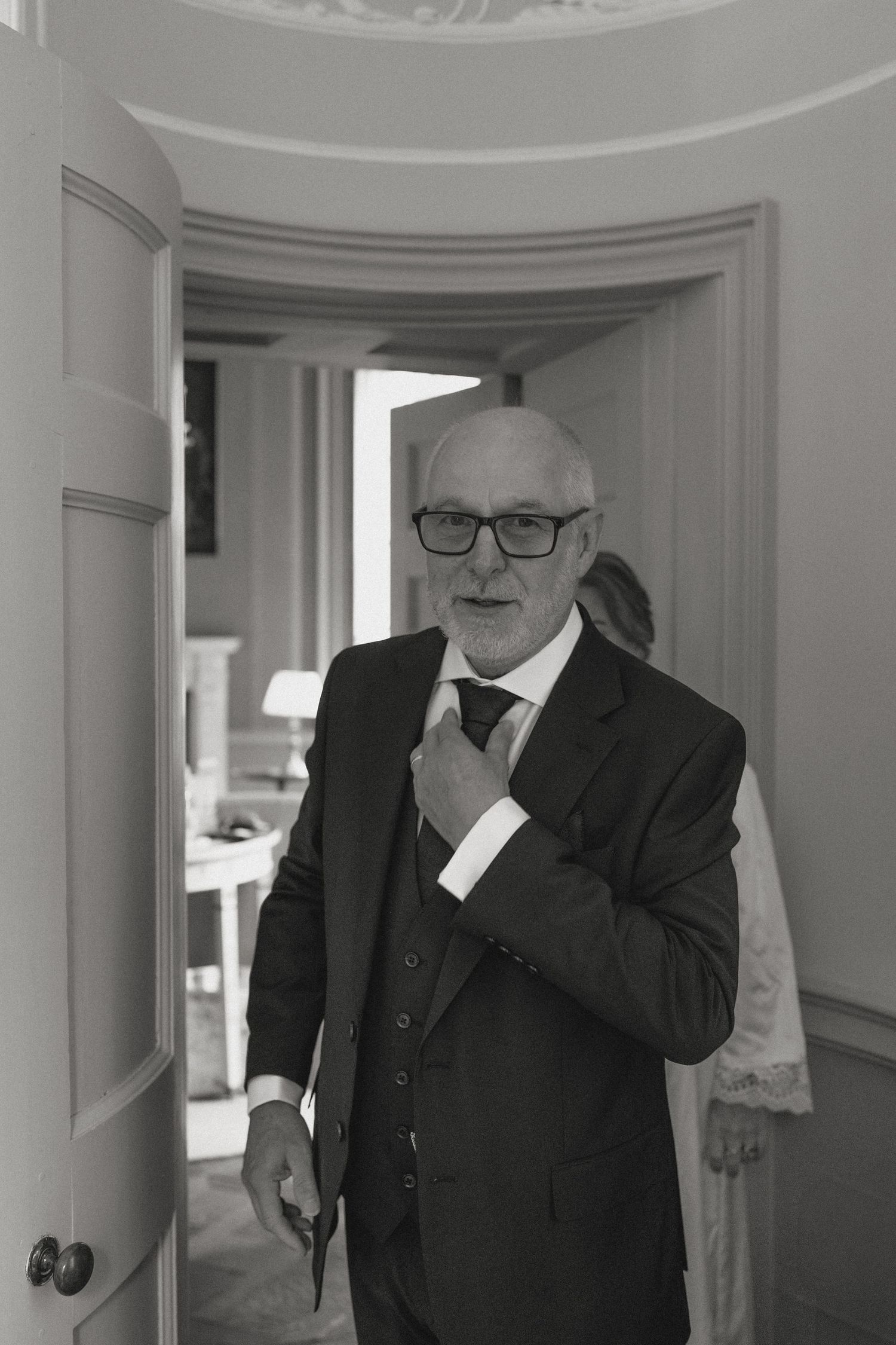 Black and white photo of men in suits standing in an elegant white room with columns.