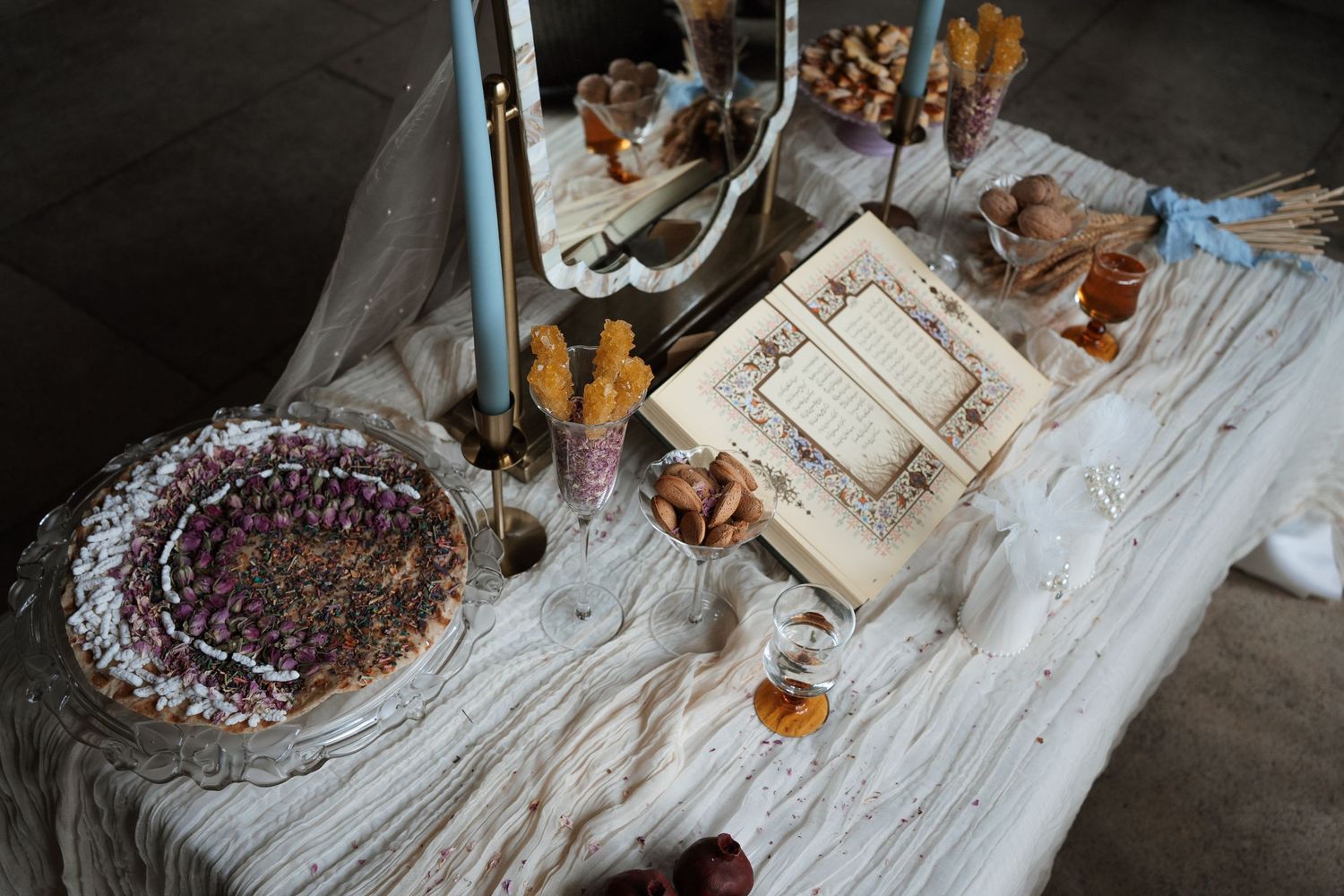 Wedding reception details with cake and decorations on a rustic white wooden table.