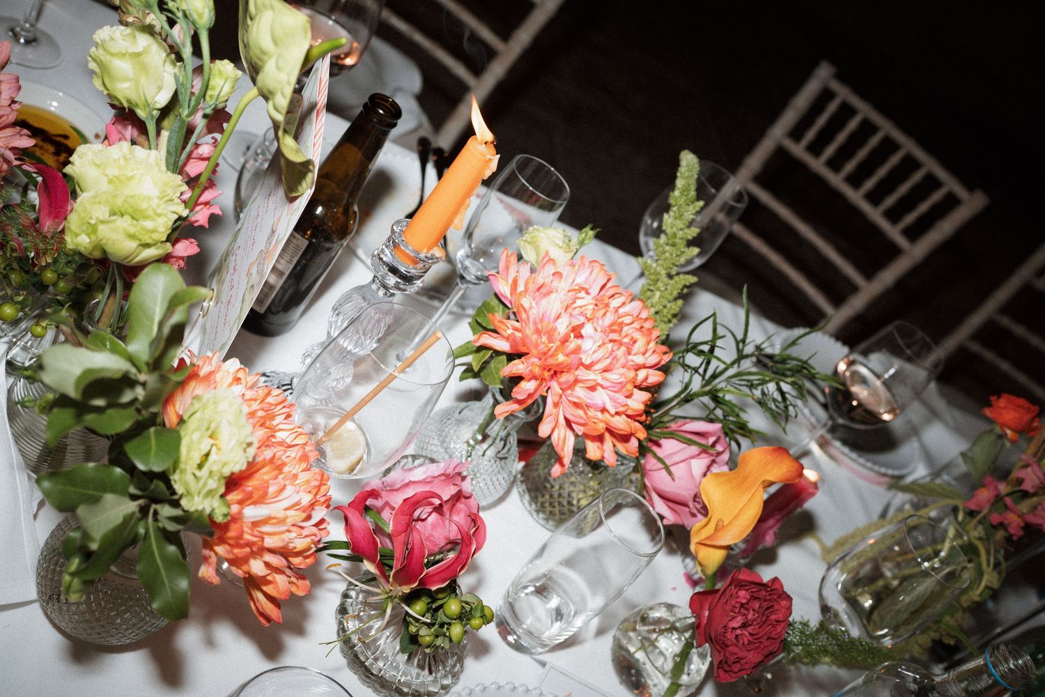 Colorful floral centerpieces with dahlias and roses on an elegant wedding reception table.