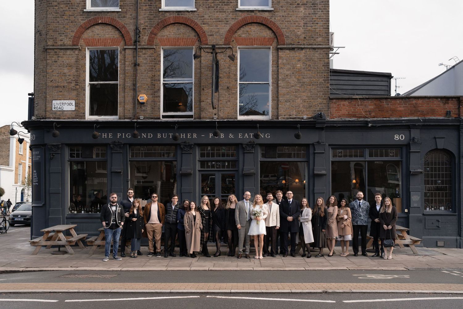 People standing in line outside a historic brick storefront.