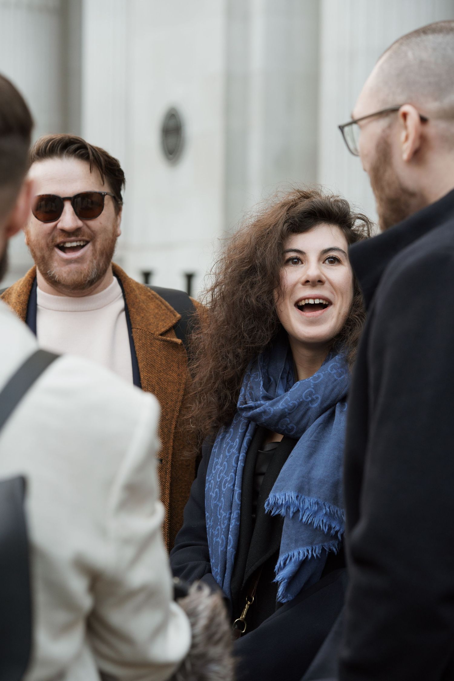 Group of people sharing a joyful moment outdoors wearing winter coats and scarves.