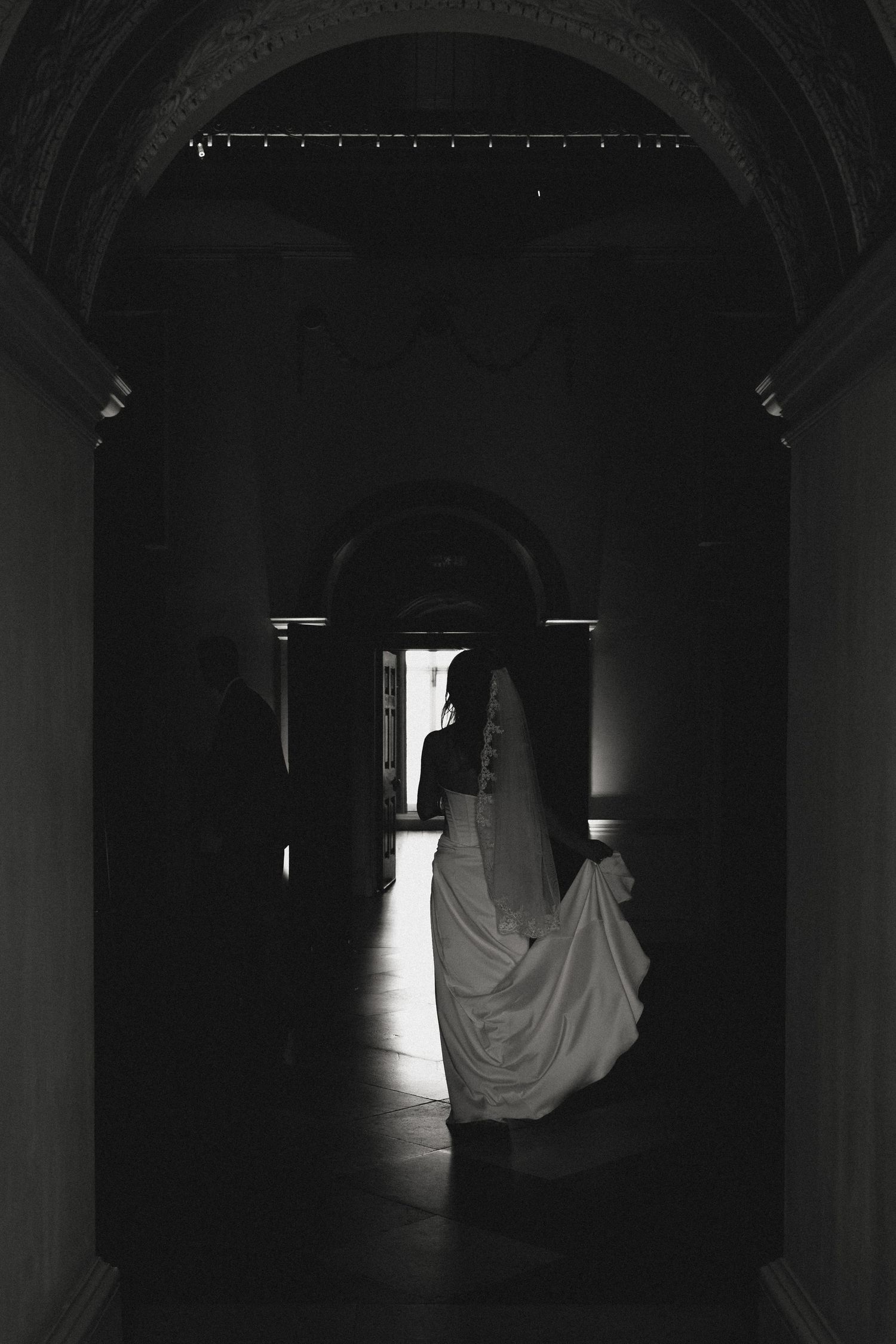 Dramatic silhouette of figures walking through dark arched hallway.