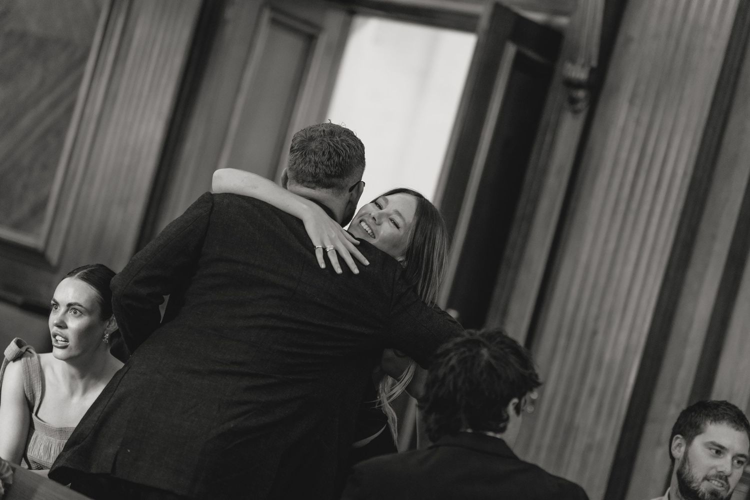 An emotional embrace captured in black and white at a formal event.