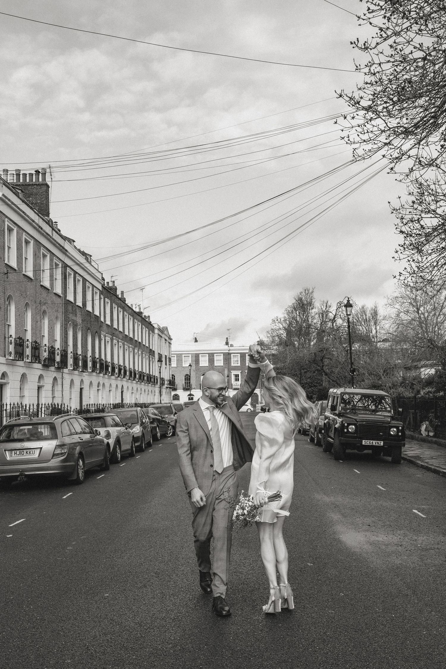 A couple dancing in a London street with Georgian townhouses and power lines in background.