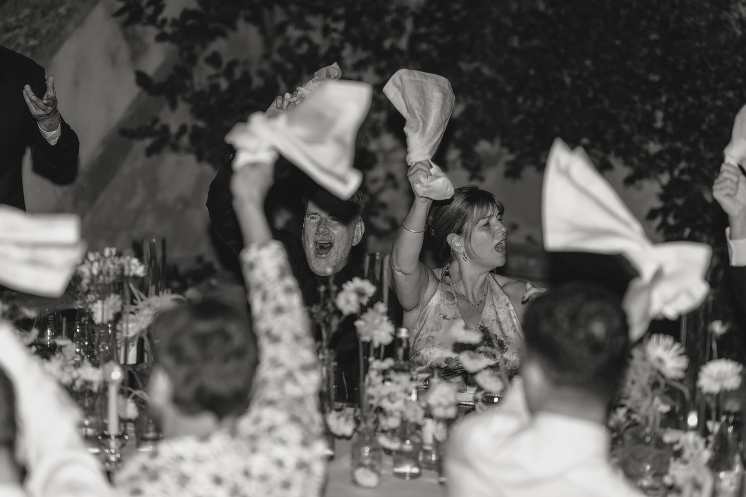 Wedding guests dancing and celebrating under twinkling lights at an outdoor reception.