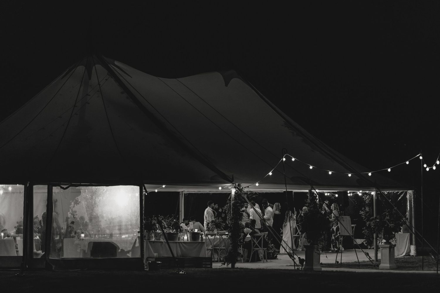 Nighttime exterior view of illuminated wedding reception tent against dark sky.
