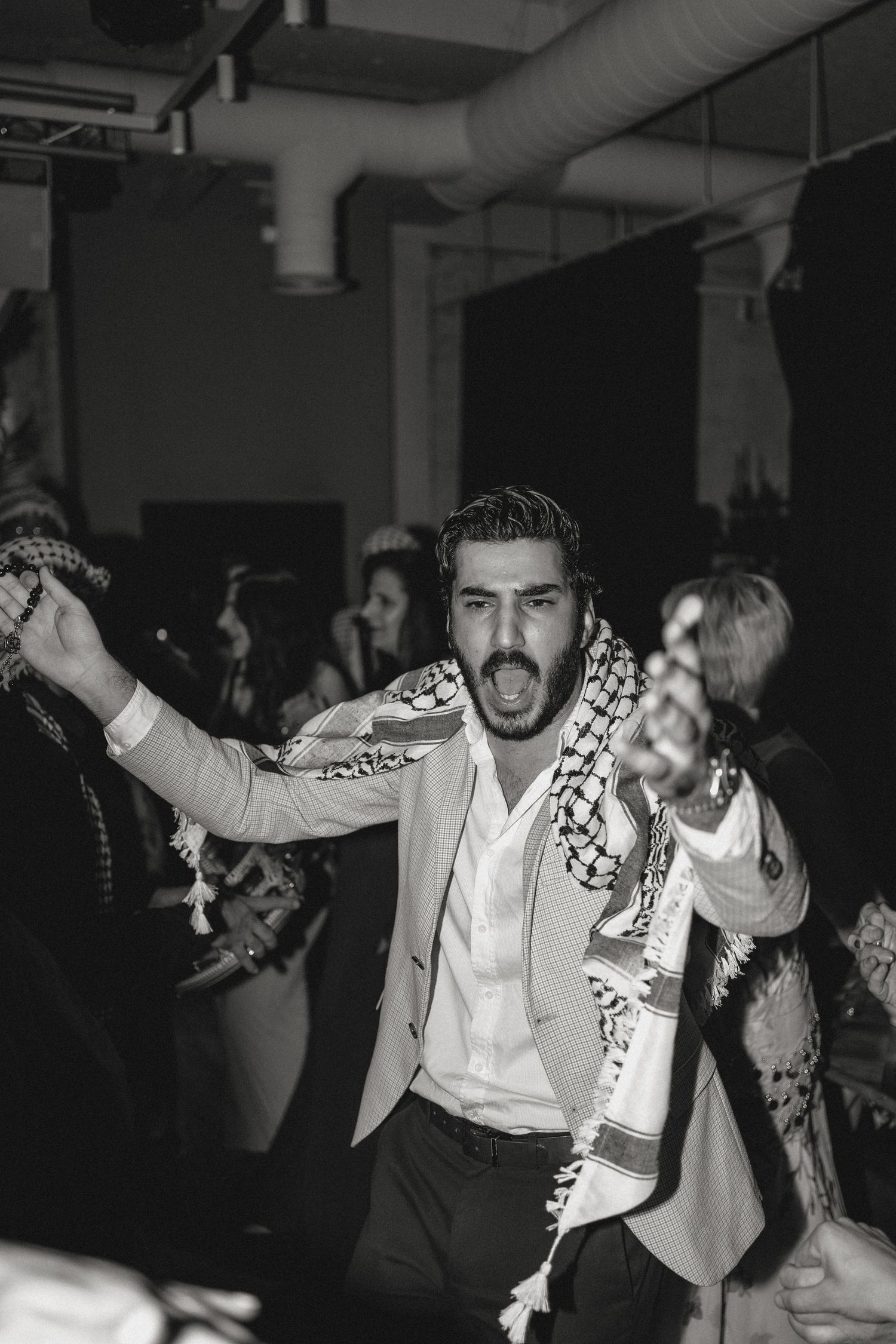 Enthusiastic dancer wearing a patterned scarf performs at a celebration.