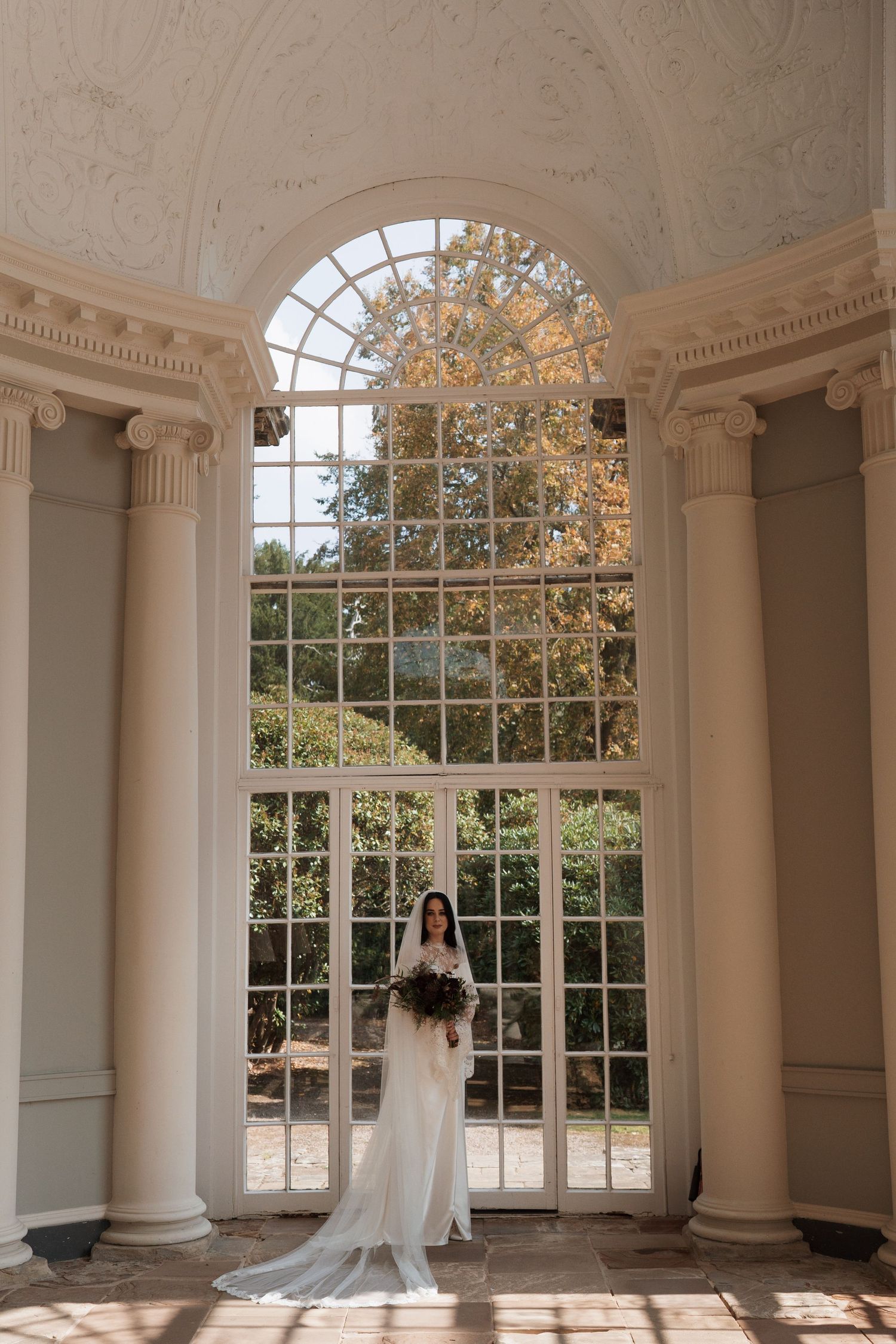Elegant room with arched windows, white columns and ornate ceiling details.