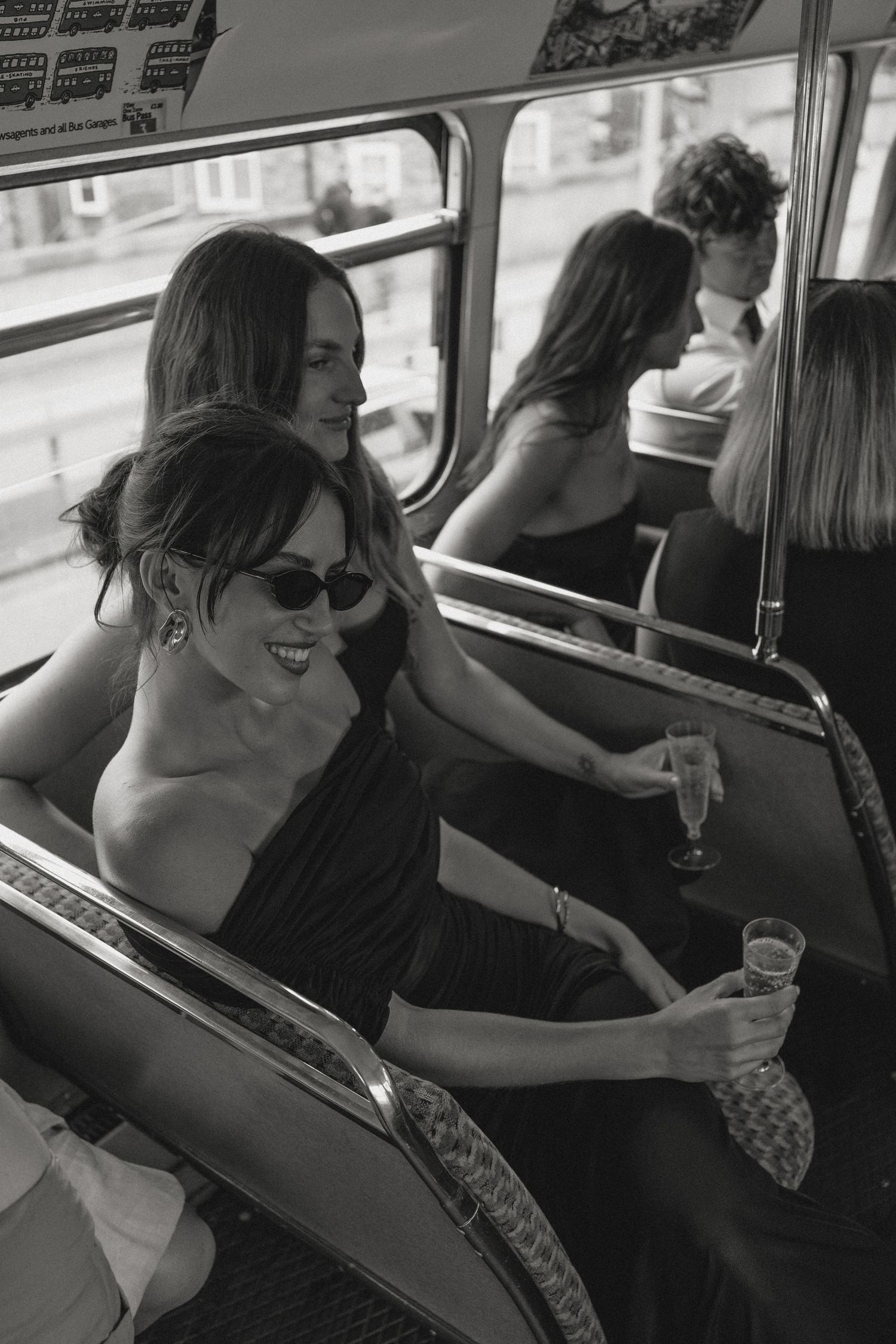 Wedding party in black dresses relaxing and celebrating inside classic bus.