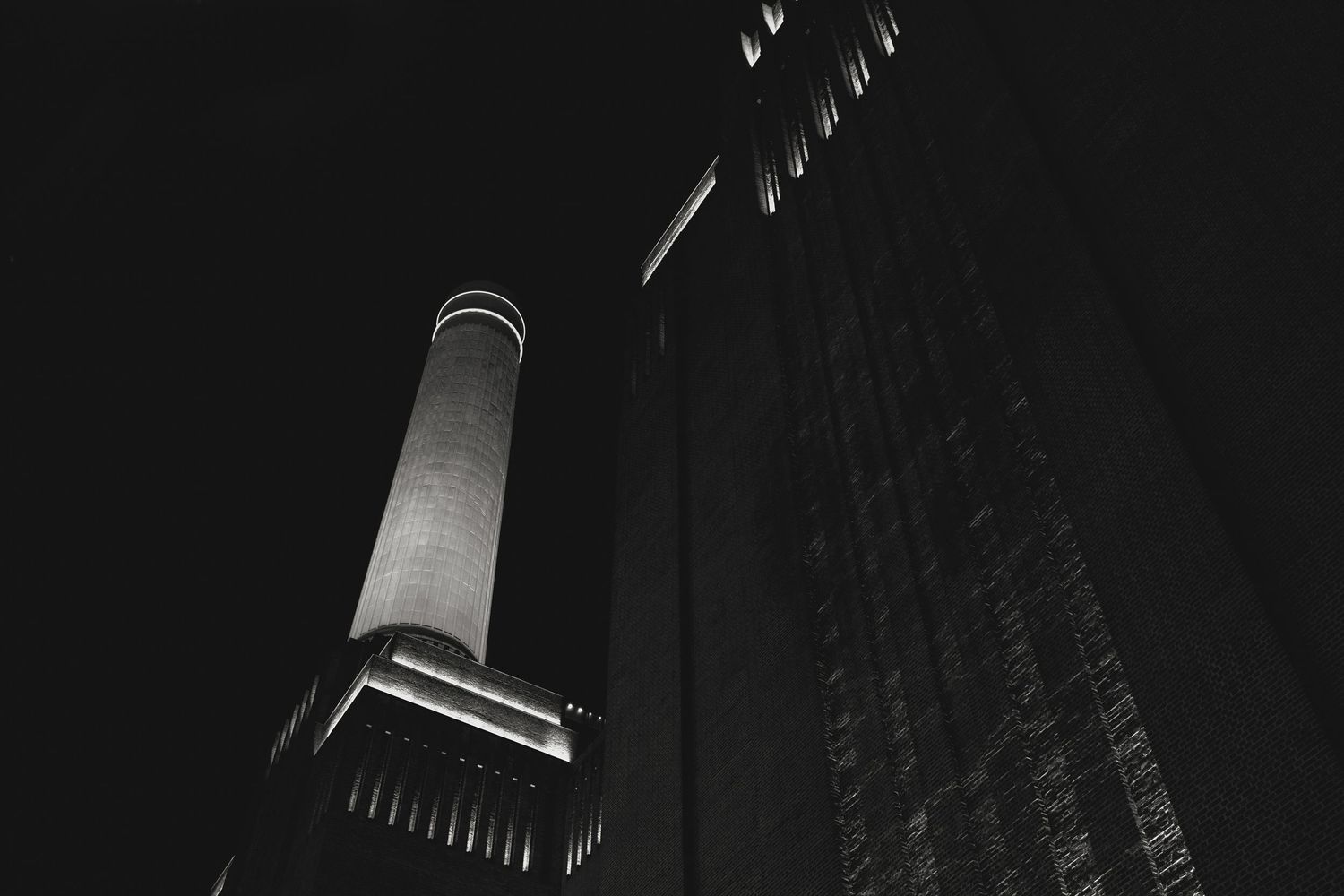 Dramatic nighttime architectural shot of an illuminated building facade with dramatic shadows and lighting.