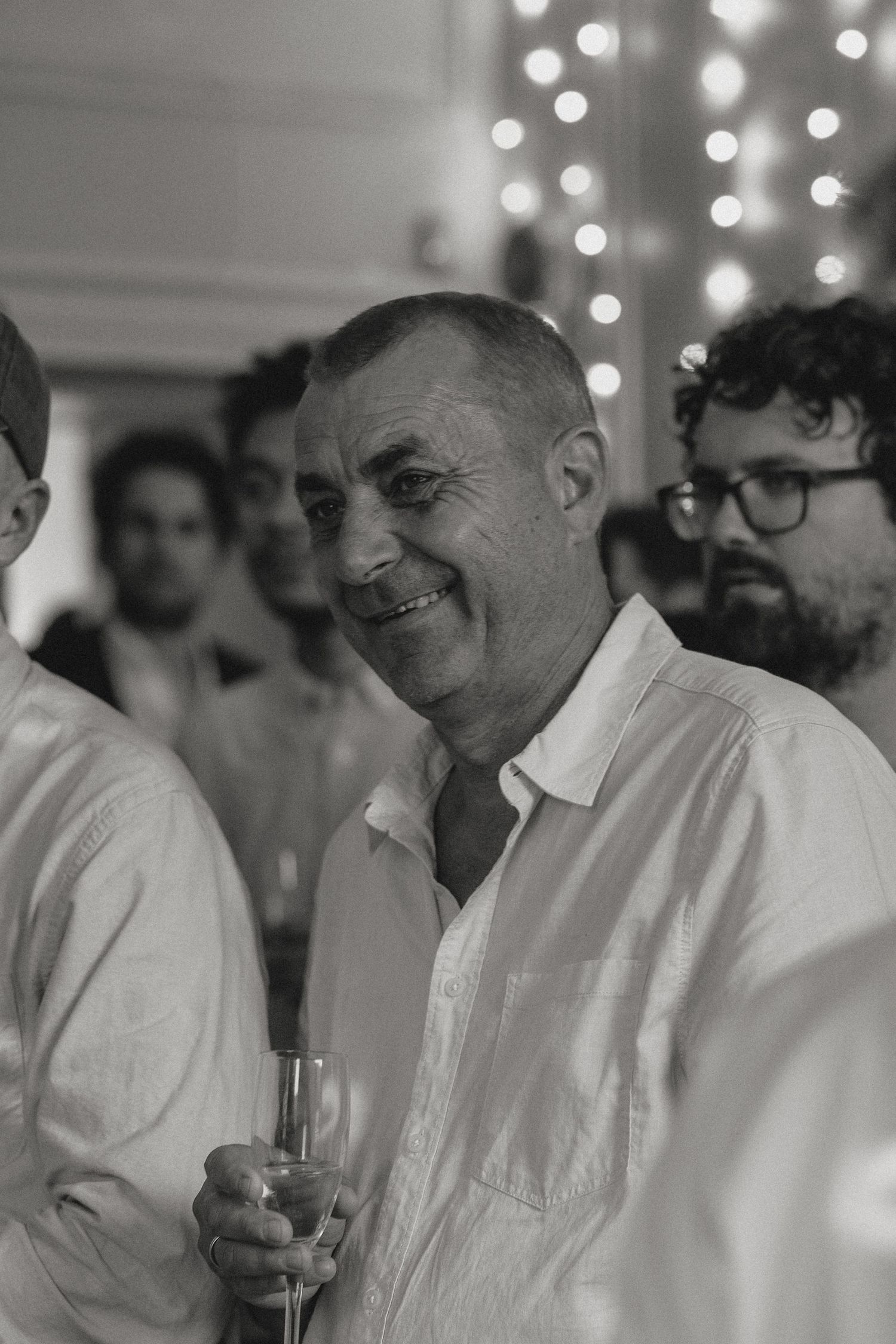 Wedding guests in white shirts enjoying drinks and conversation at an evening reception.