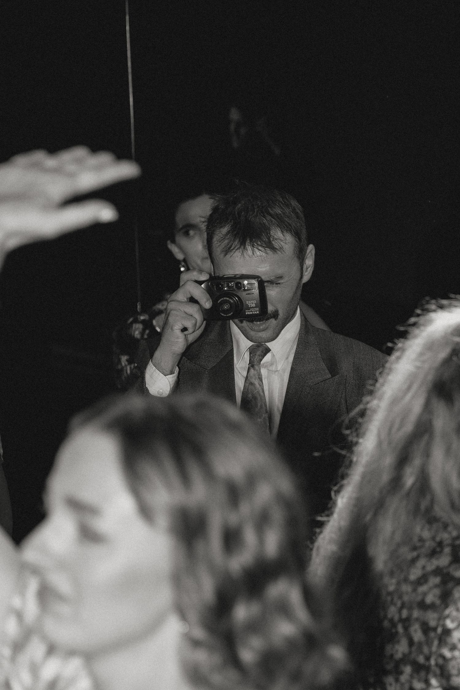 Black and white photo of people dancing at a dimly lit party.