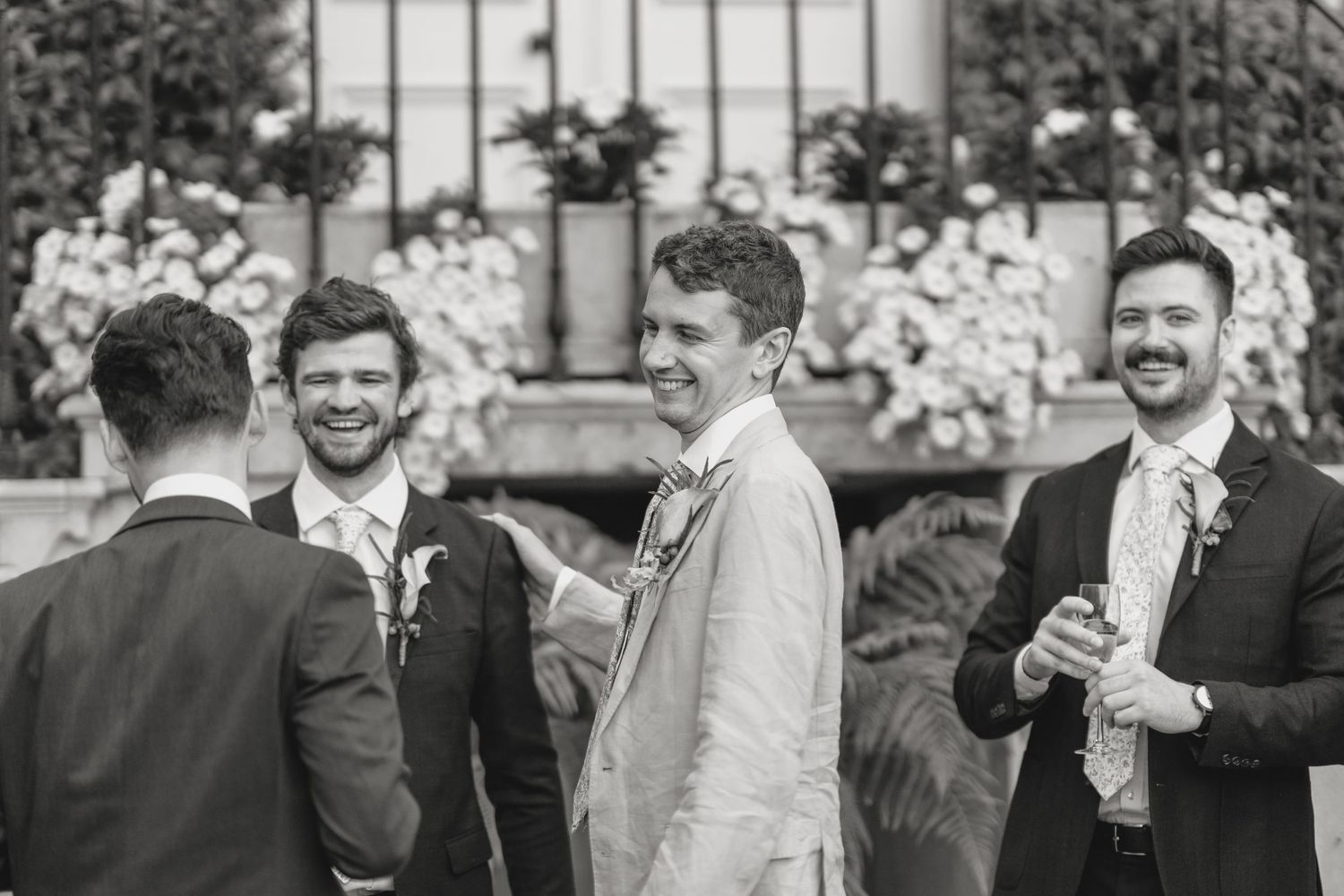 Wedding guests enjoying drinks and conversation in an outdoor garden setting.