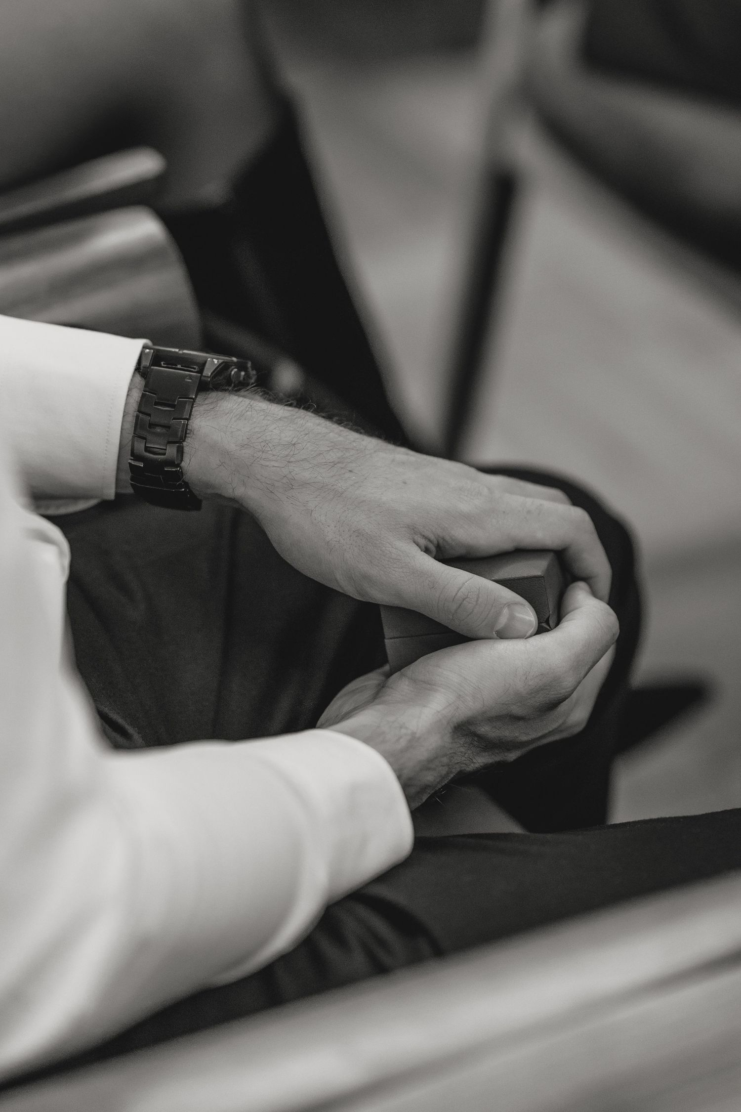 Close-up black and white shot of hands exchanging rings during a wedding ceremony.