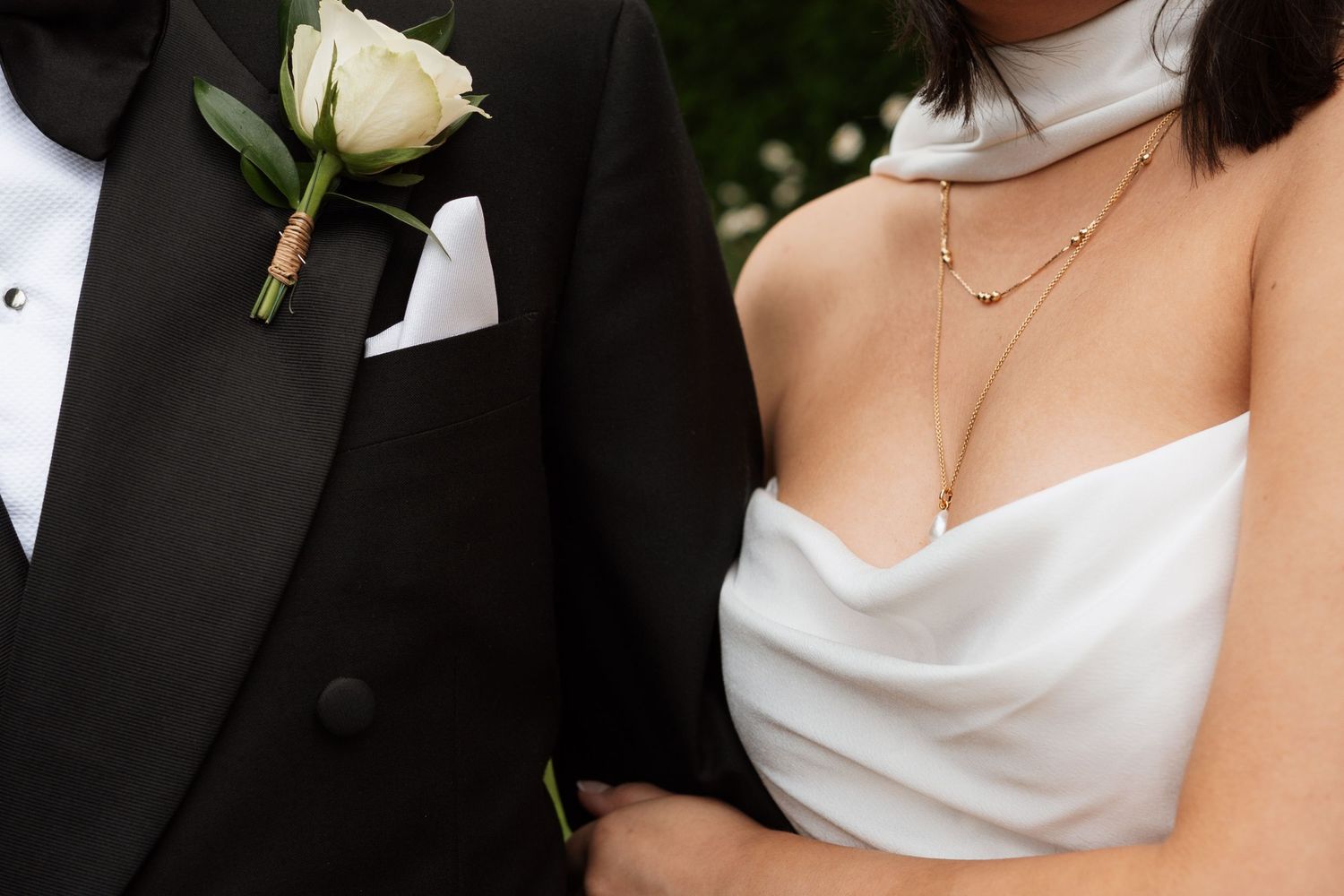 Close-up details of formal wedding attire including a white boutonniere and dress.