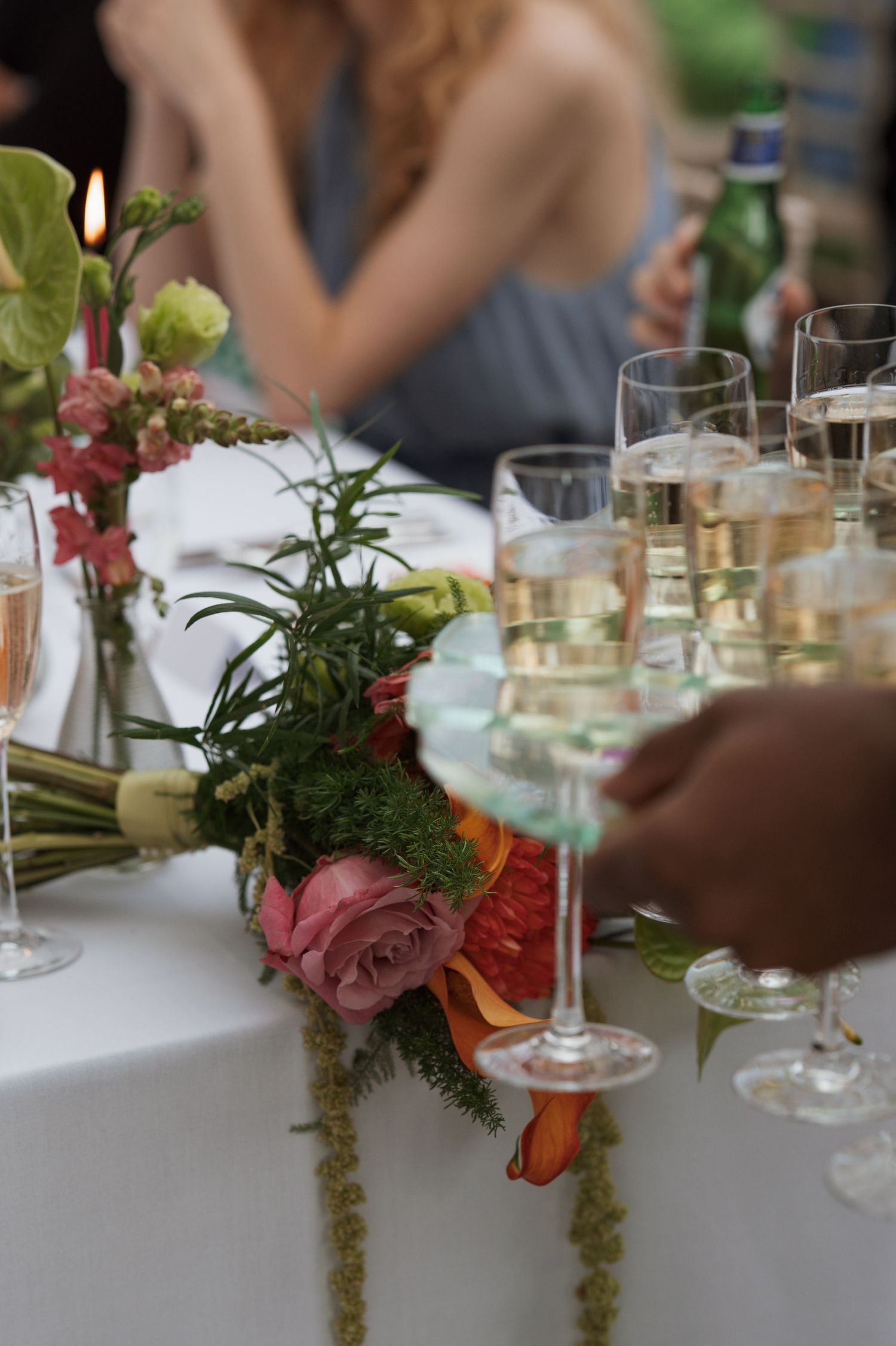 Elegant table setting with champagne glasses and pink floral arrangements at a wedding reception.