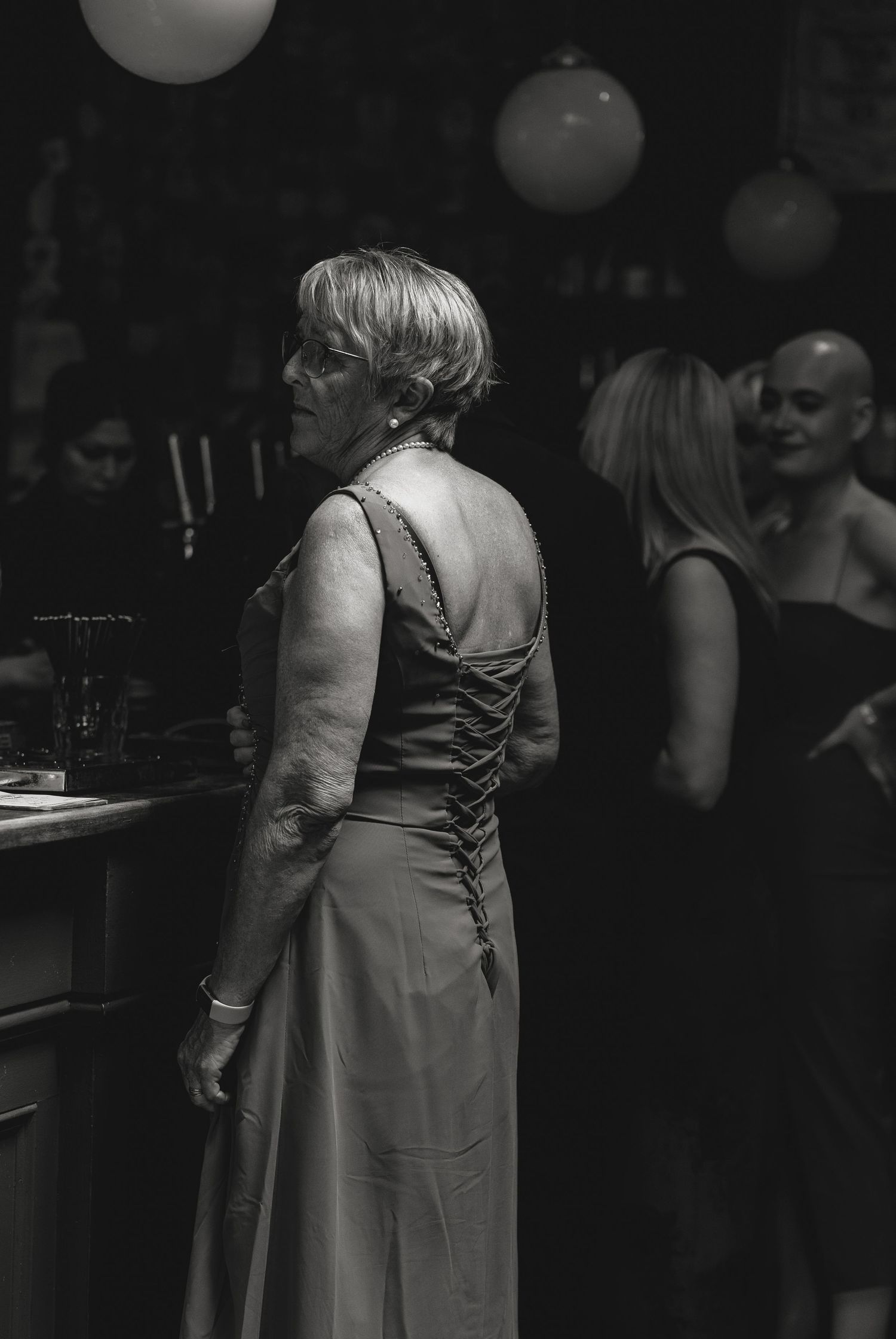 People in formal attire at an evening event shown in black and white photography.