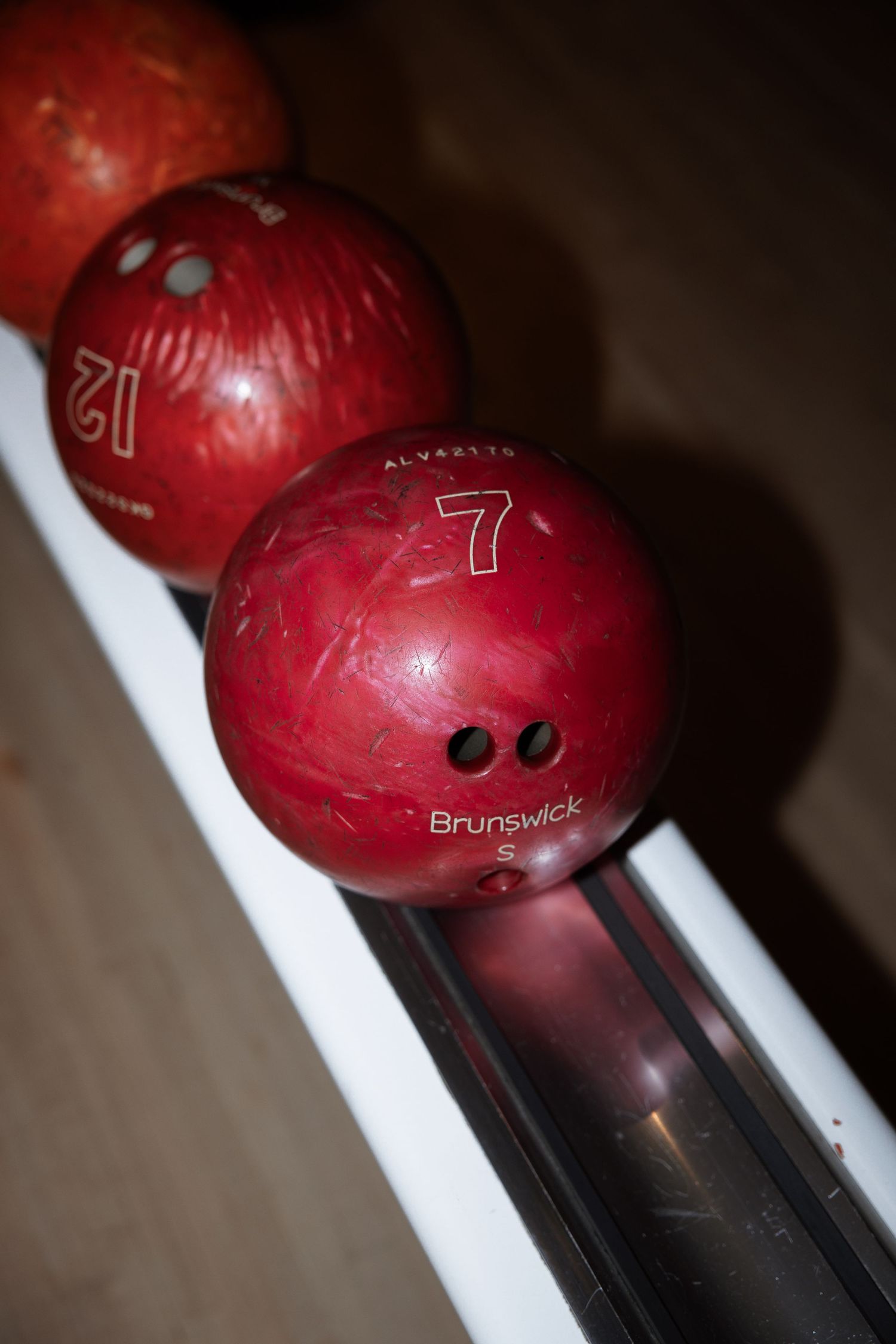 Close-up of red Brunswick bowling balls lined up in a row showing their numbers.