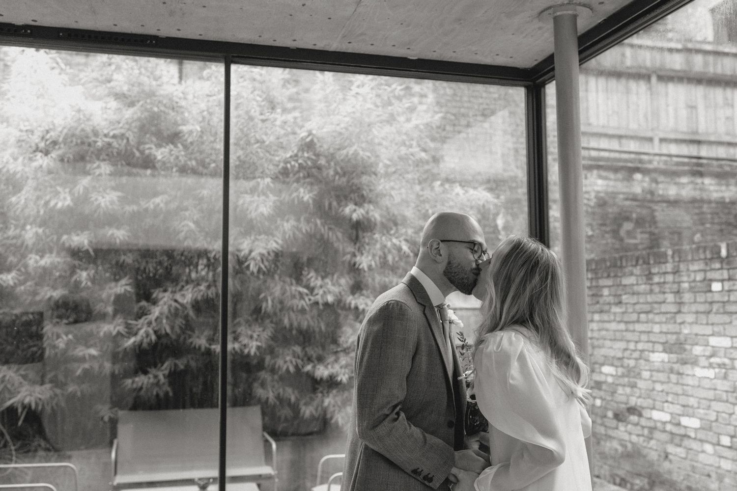 A series of black and white shots capturing a first look moment in a modern interior space.