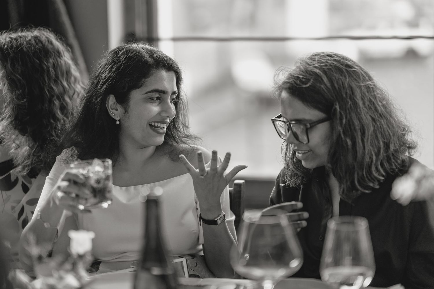 Black and white photo of people engaged in animated conversation at social gathering.