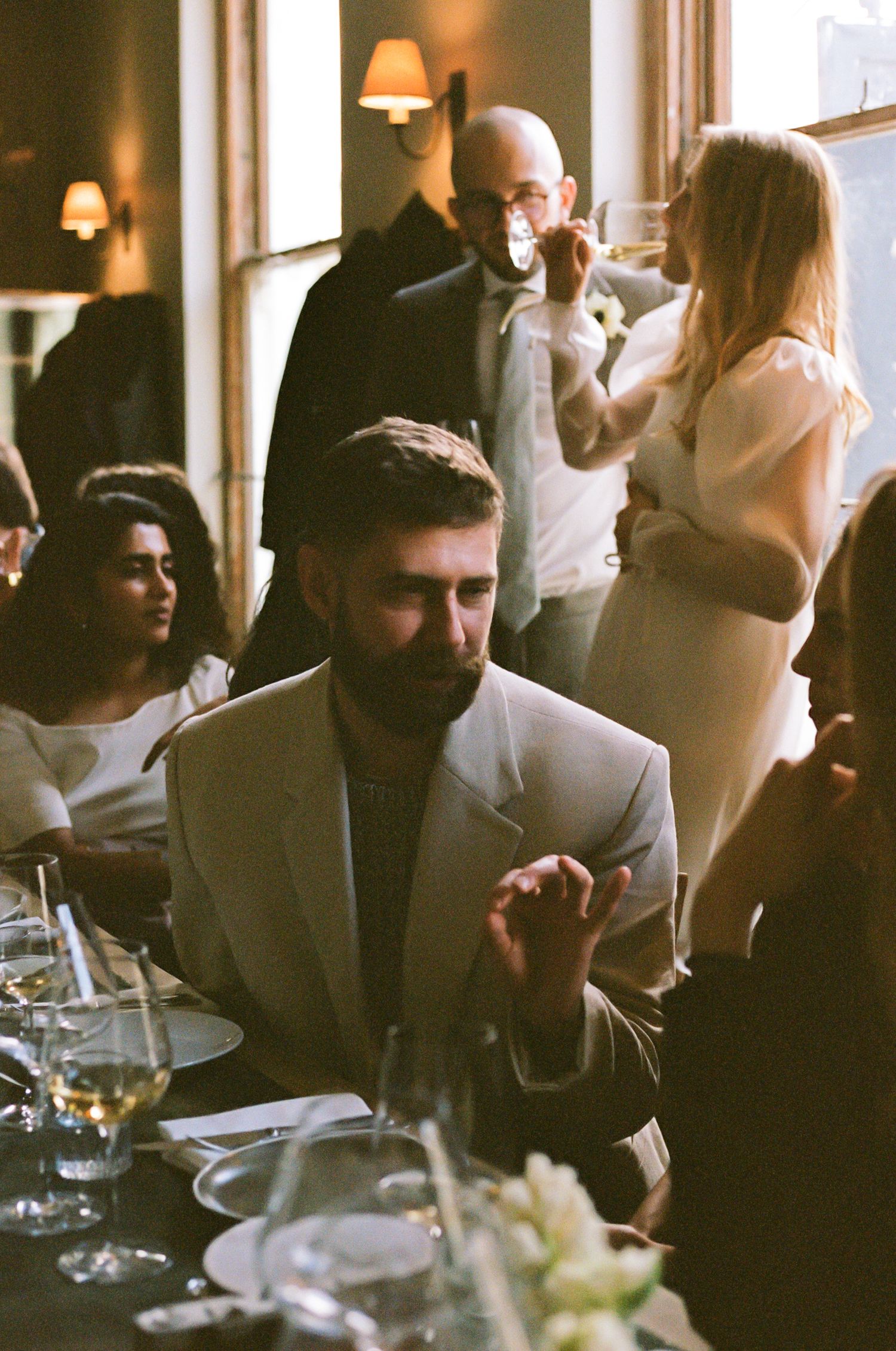 Candid moments captured during wedding reception dinner in warm ambient lighting.