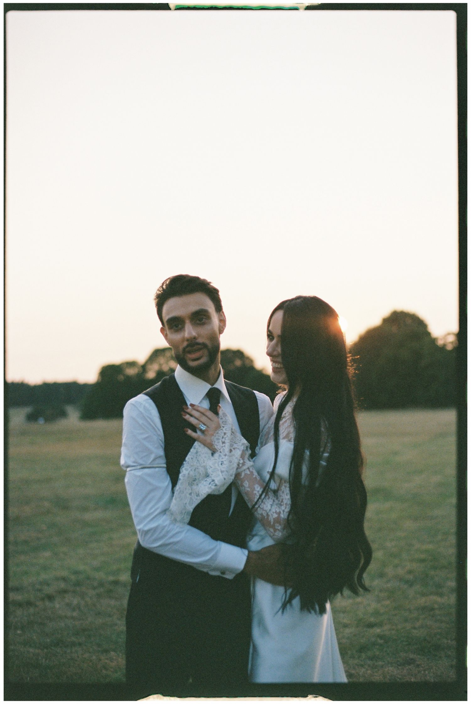 Romantic sunset portrait of newlyweds in formal attire.