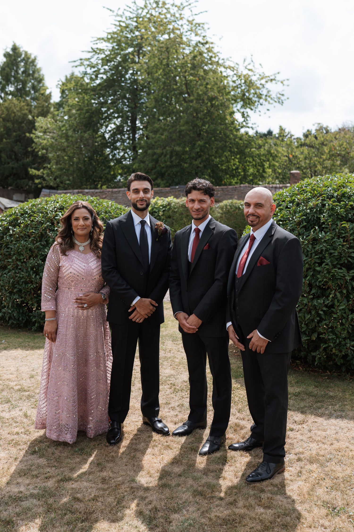 Small group in formal attire posing together in a garden setting.