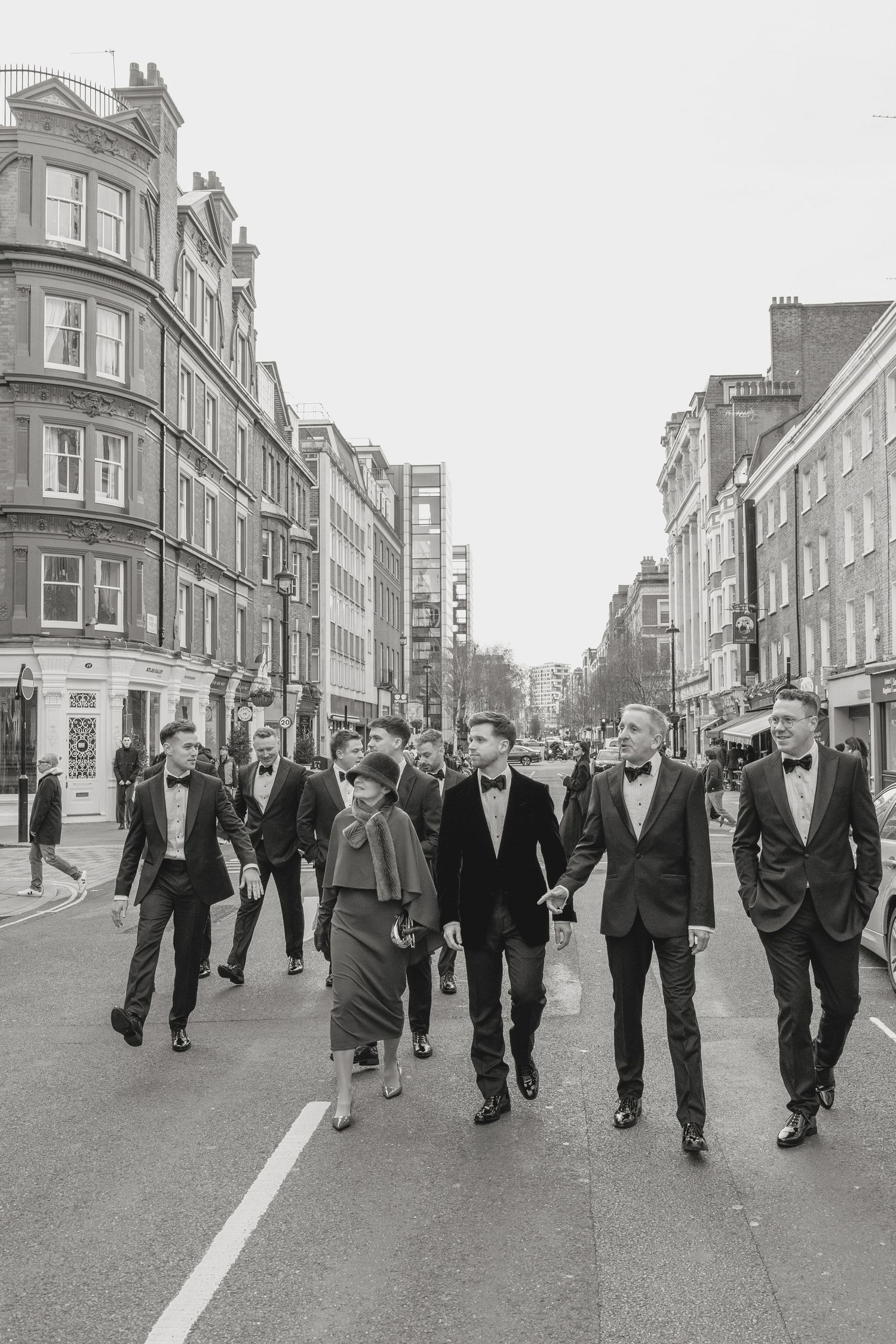 People walking down a vintage London street lined with Victorian architecture.