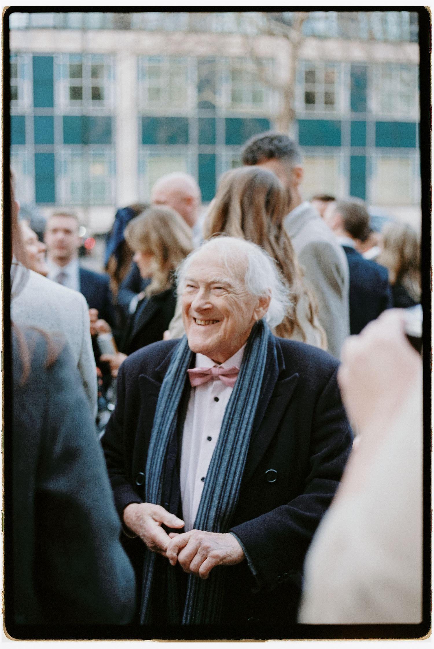 Joyful guest in formal attire enjoying a festive gathering outdoors.