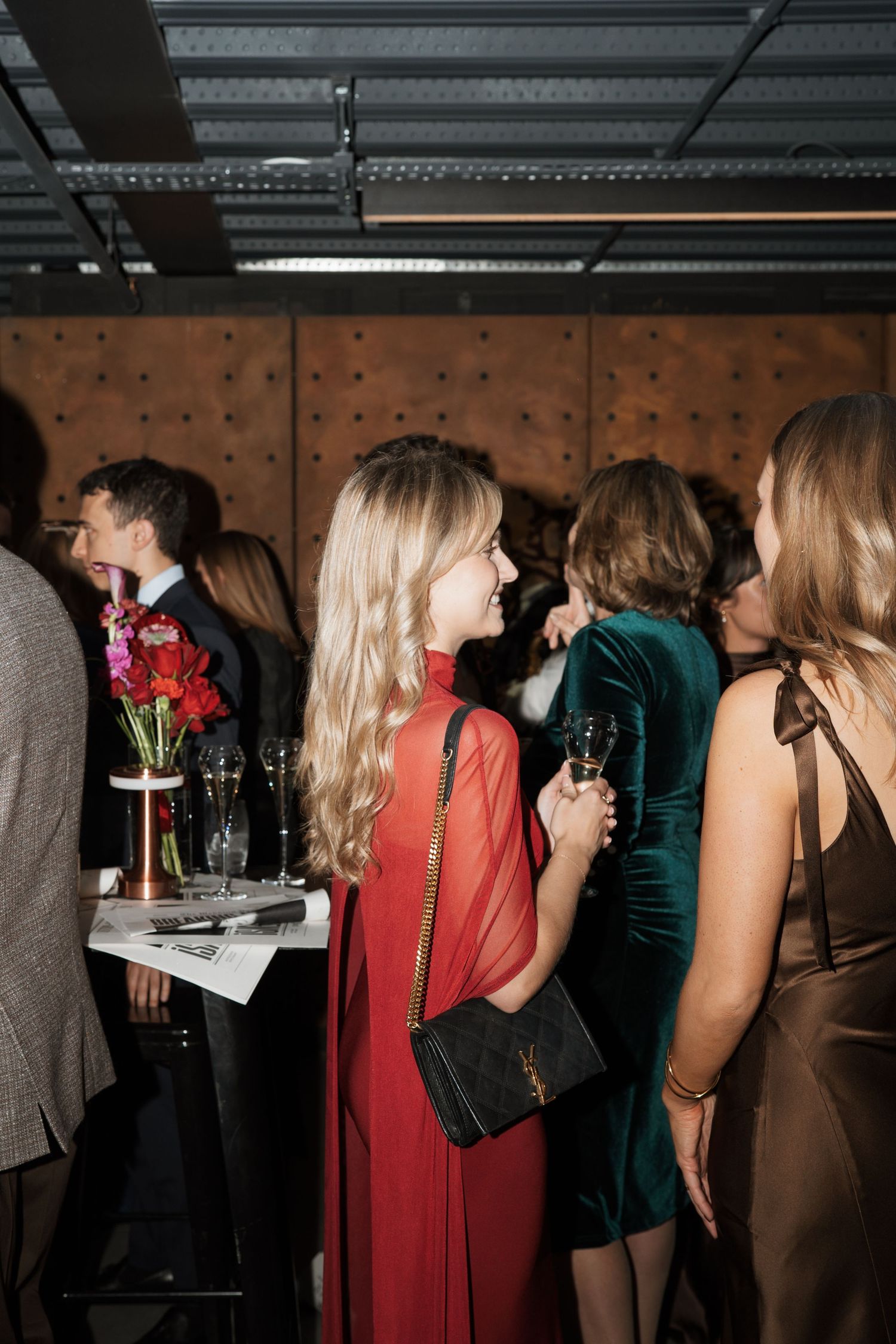 Guests mingling at a party with red and dark colored formal attire.