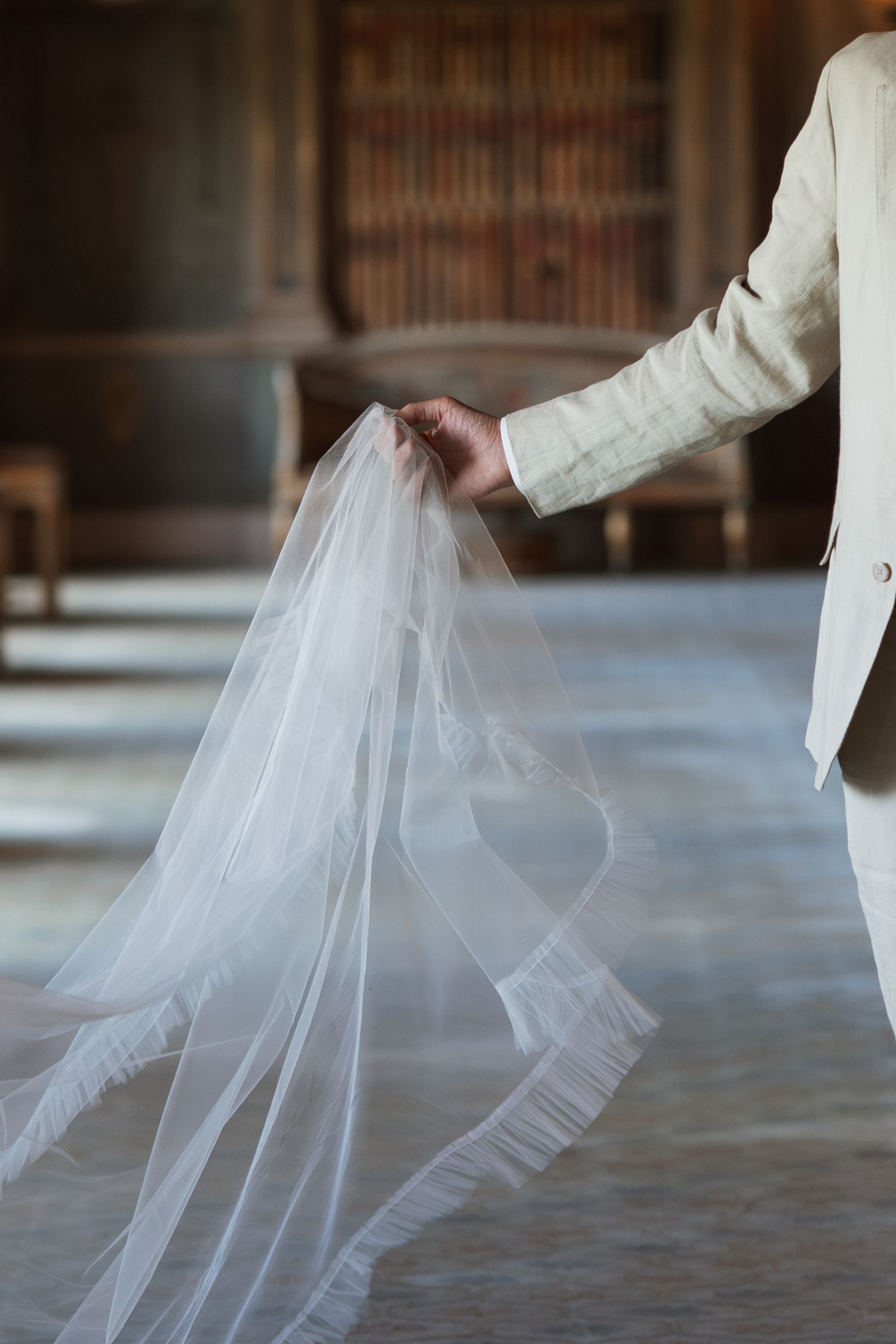 Flowing white wedding dress fabric creates ethereal movement in an indoor setting.