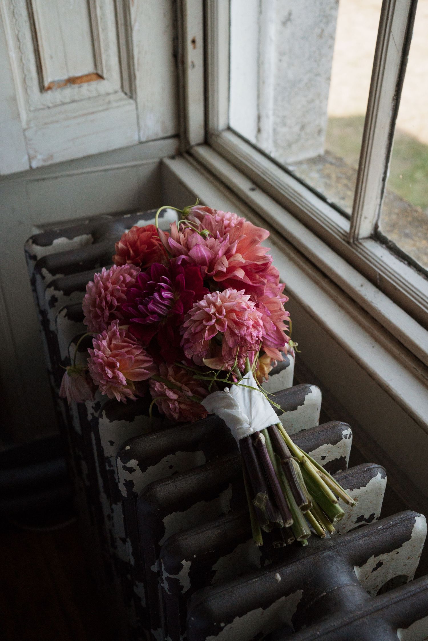 Pink dahlia bouquet resting on windowsill in natural light.