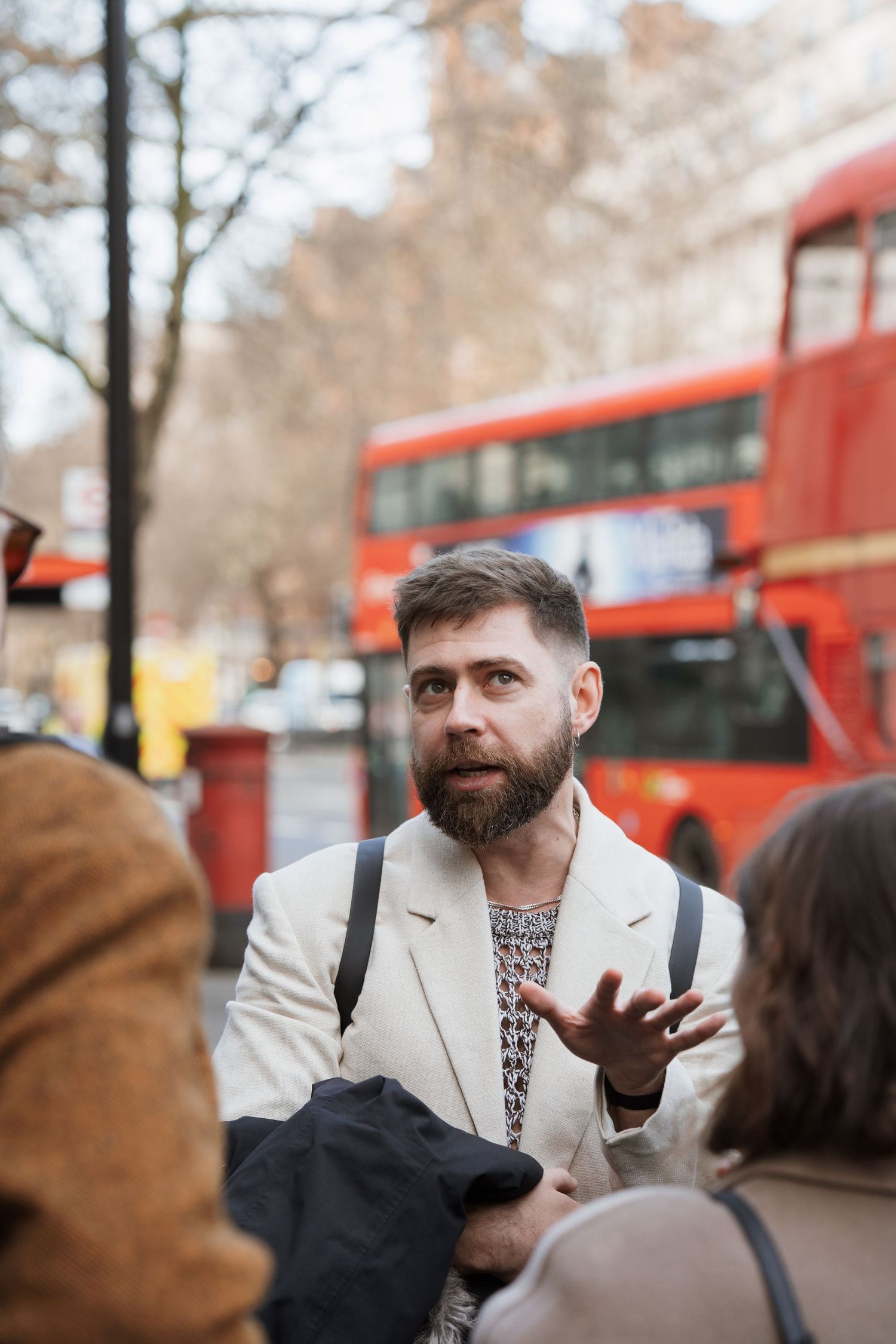 Red double-decker buses visible in the background of a London street scene.