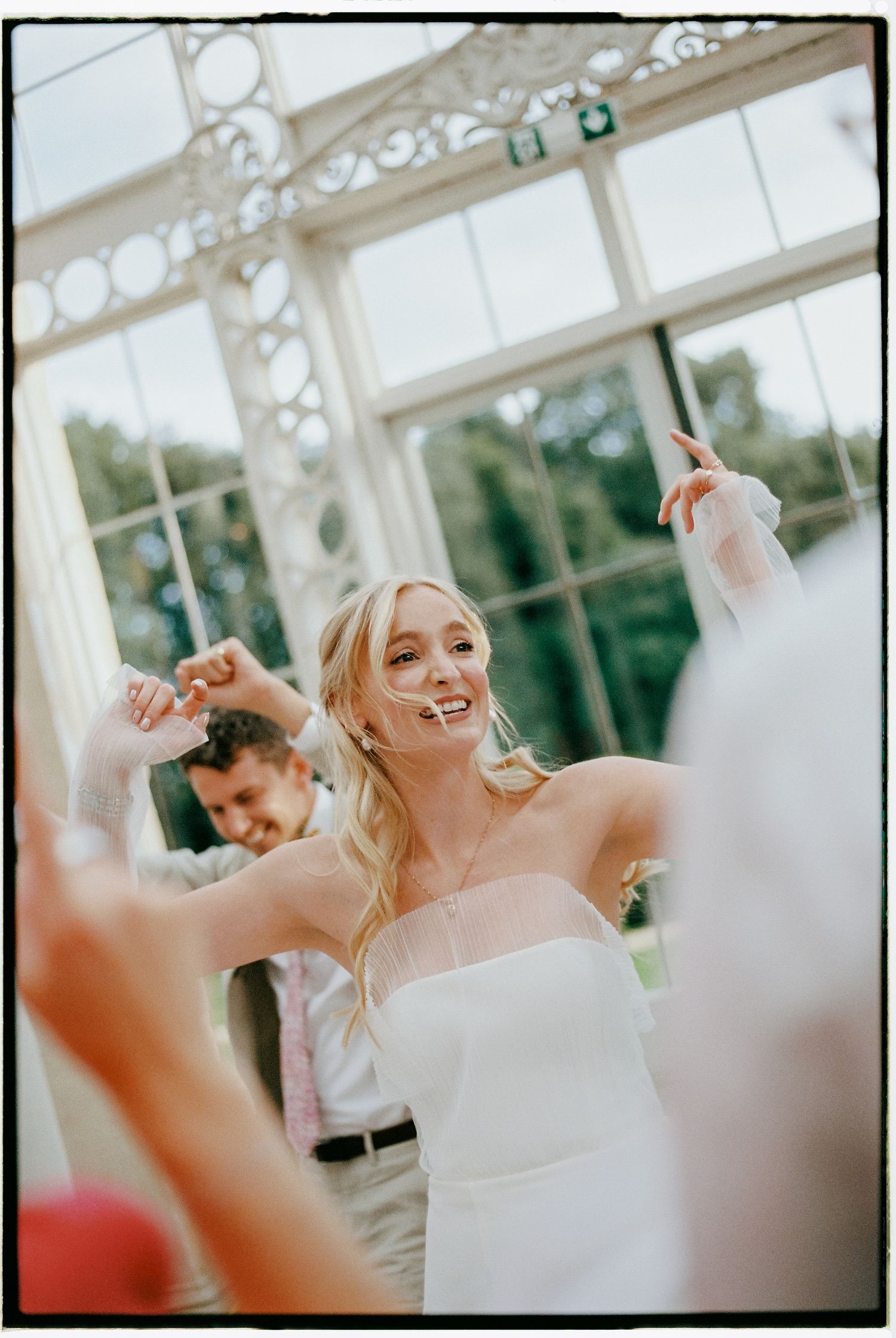 Wedding celebration with guests dancing and celebrating in a bright indoor venue.