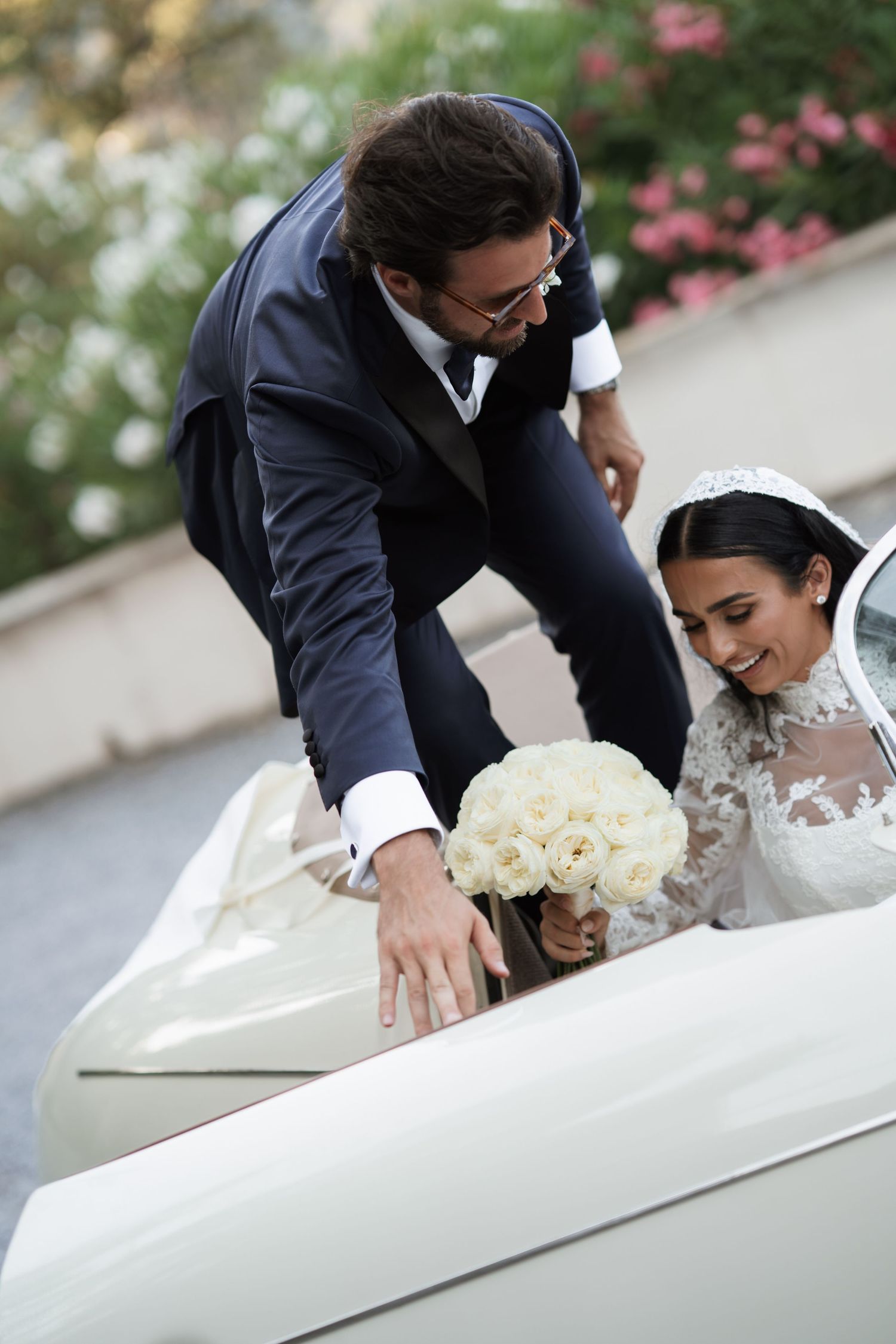A couple in wedding attire share an intimate moment with white roses.