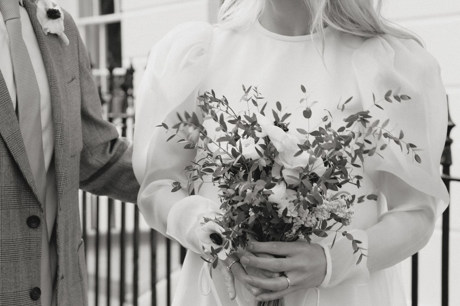 Close-up details of white wedding bouquet with delicate greenery and flowers.